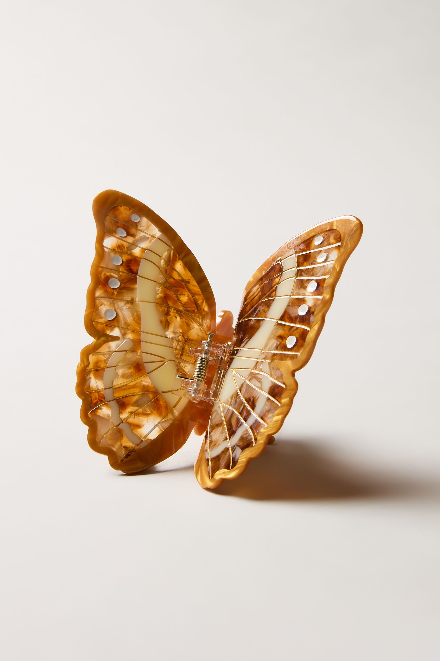 The Hand-Painted Morpho Butterfly Hair Clip is a sculptural accessory with marbled brown and cream plastic, a metal spring and clasp, shown on a neutral background.