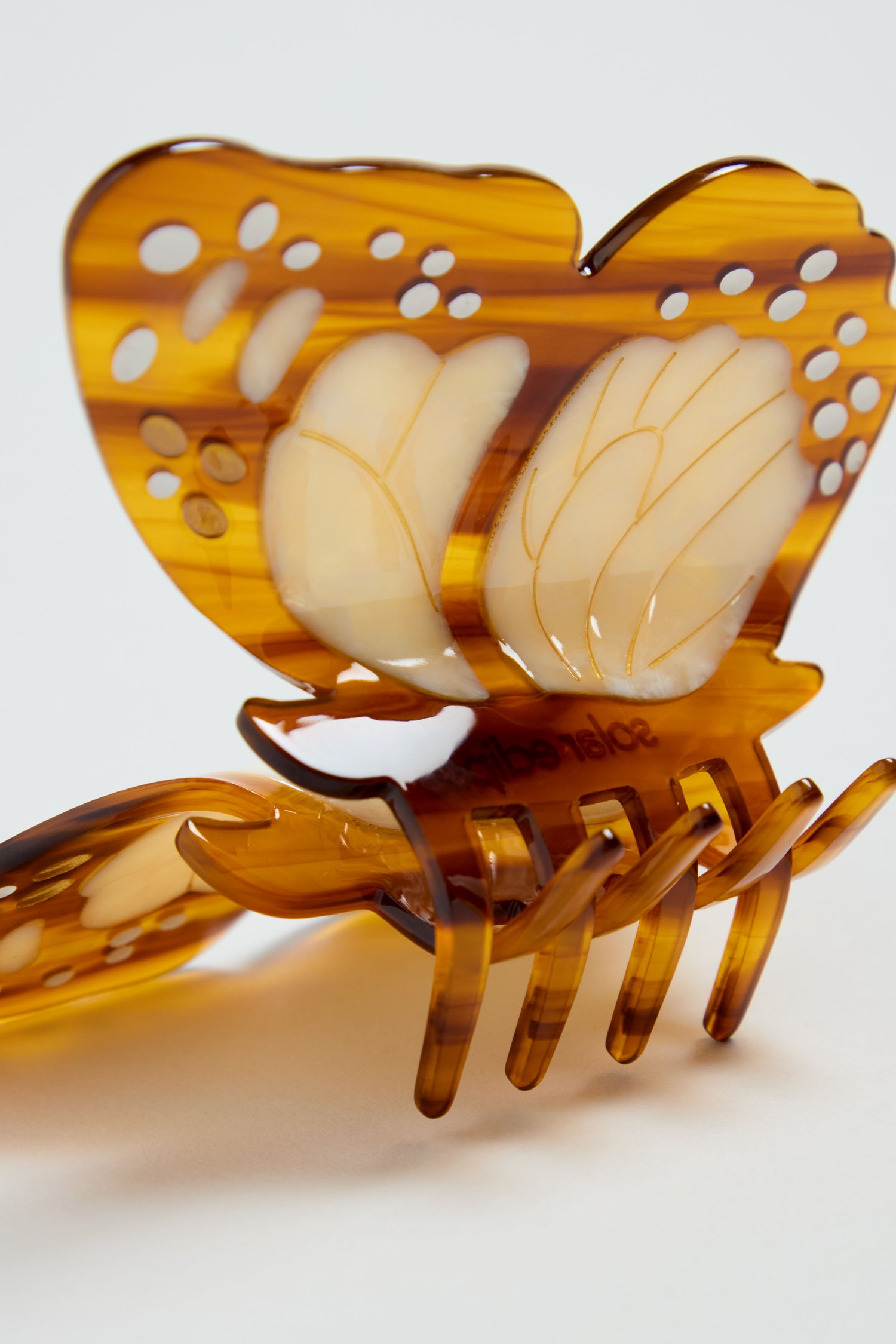 Close-up of a Hand-painted Monarch Butterfly Hair Clip, an eco-friendly hair accessory featuring brown and cream translucent wings patterned like a real butterfly.
