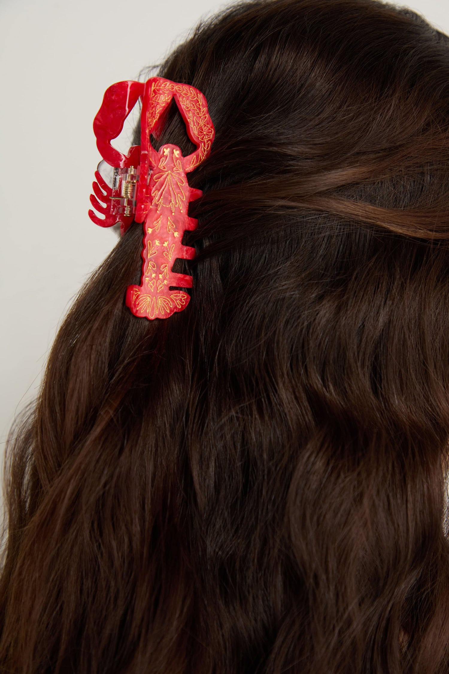 A person with long brown hair is wearing a Hand-painted Lobster Hair Clip, an eco-friendly and fun coastal accessory, on the back of their head.