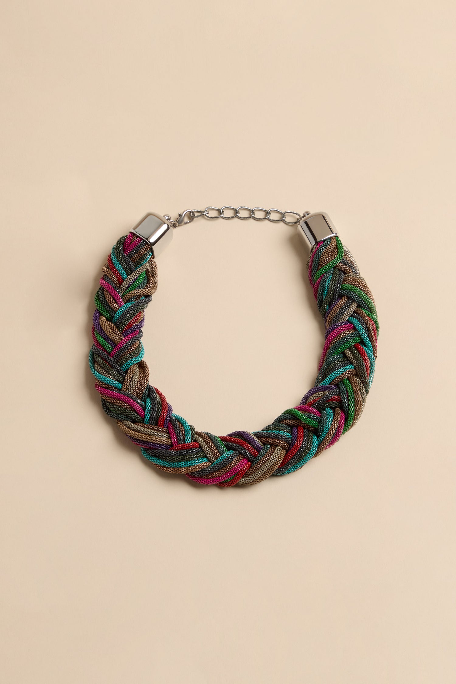 The Braided Rainbow Chain Necklace is a chunky collar made of interwoven mesh cords in shades of green, blue, pink, and metallic brown, featuring silver-tone end caps and a chain extender.