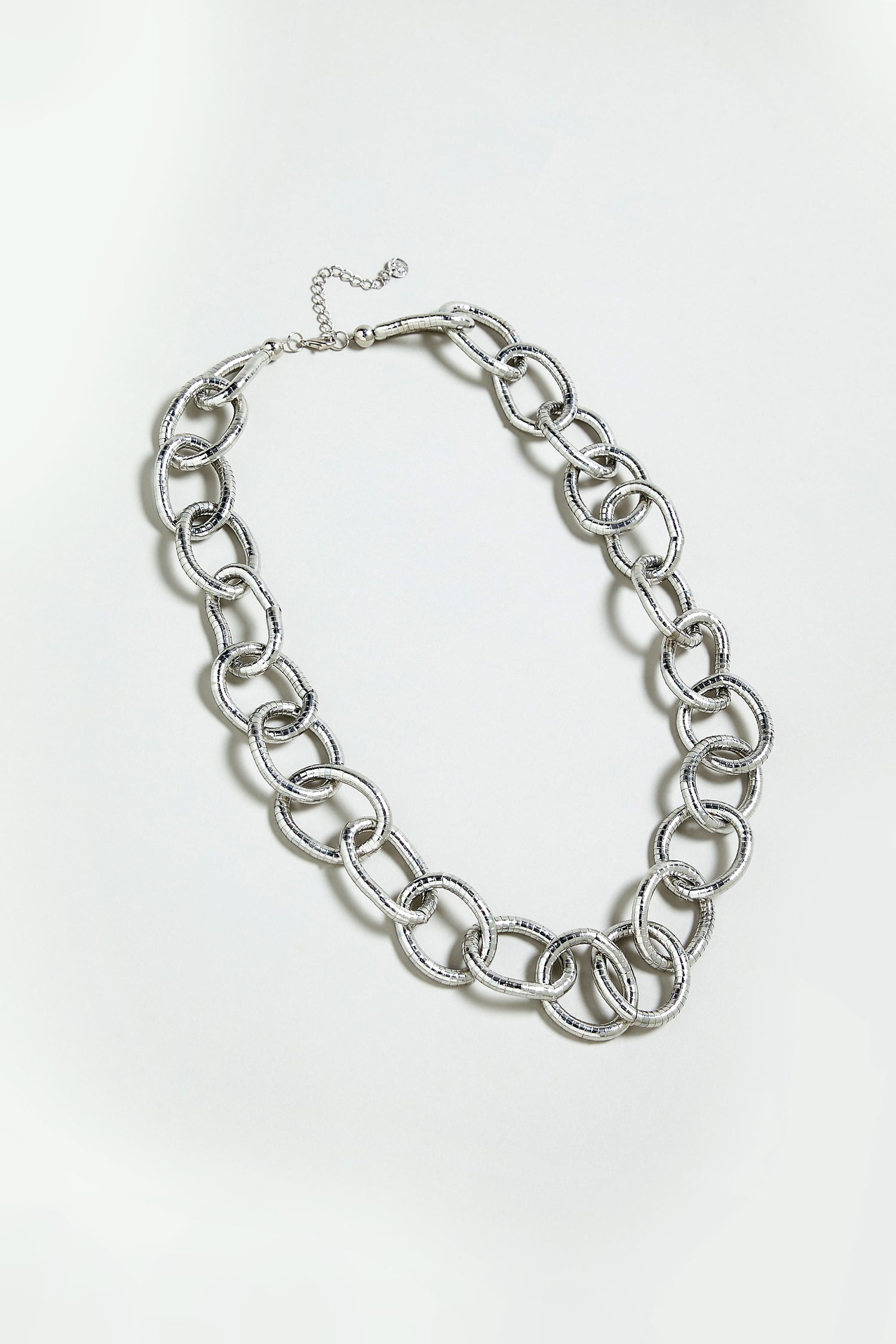 The Long Links Necklace features an oversized silver chain with large, textured interlocking links and an adjustable clasp, displayed on a plain light background.