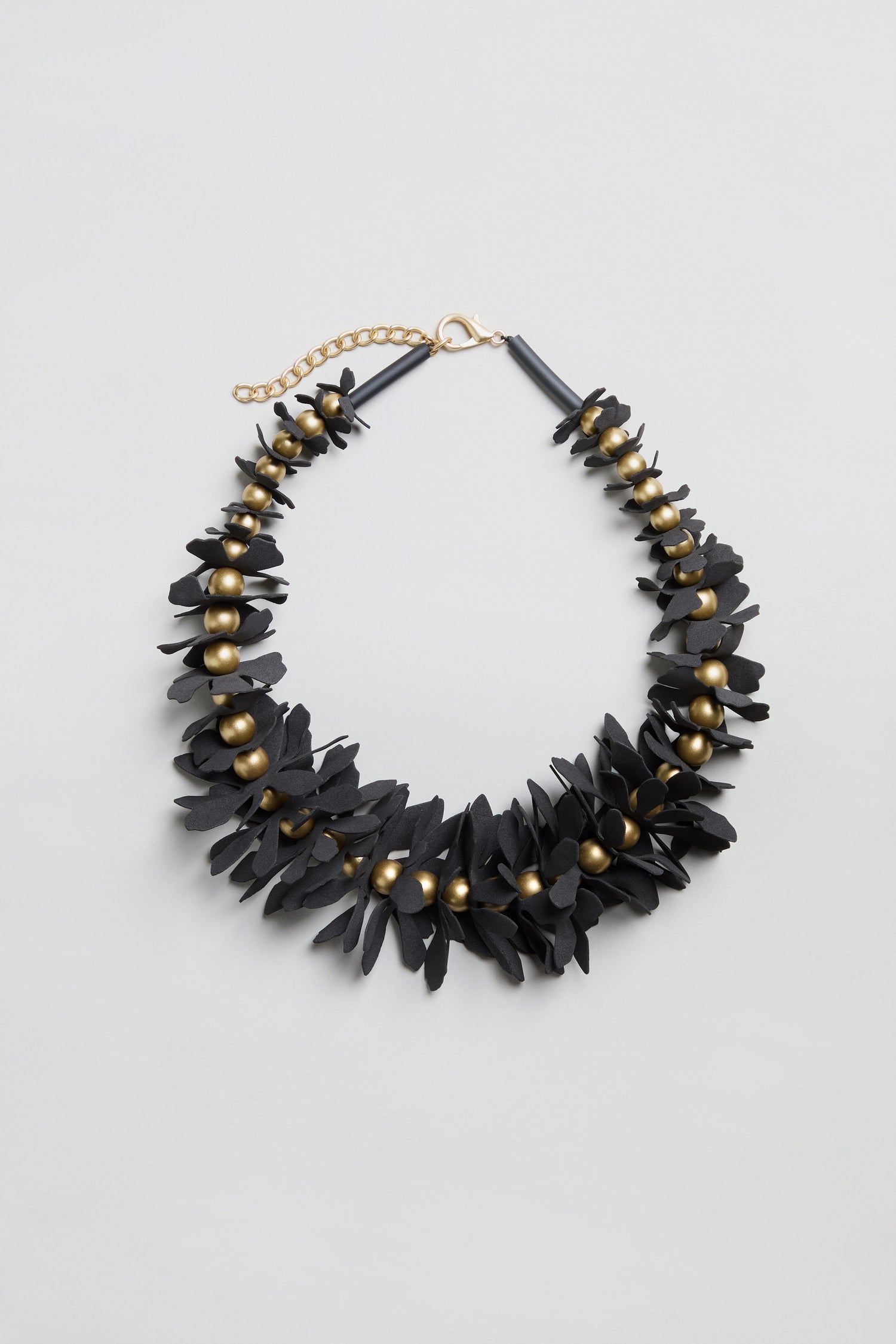 Flower Bead Necklace showcasing black floral elements with gold accent beads and an adjustable gold chain clasp, designed in a collar-length style and presented on a plain light gray background.