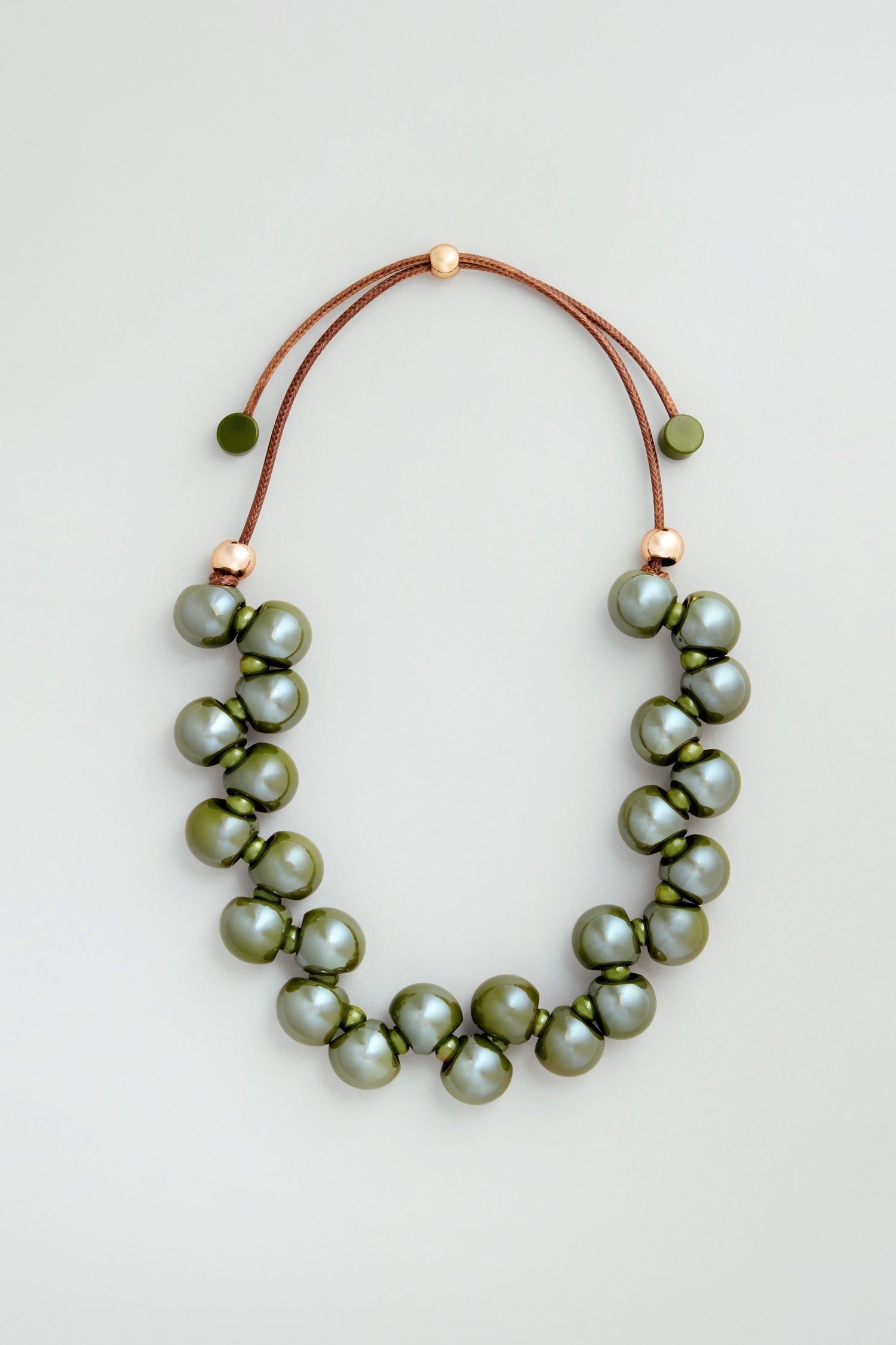 The Macrame Resin Bead Necklace features large, round olive-green resin beads on a brown cord with gold accents and an adjustable closure for a perfect fit.