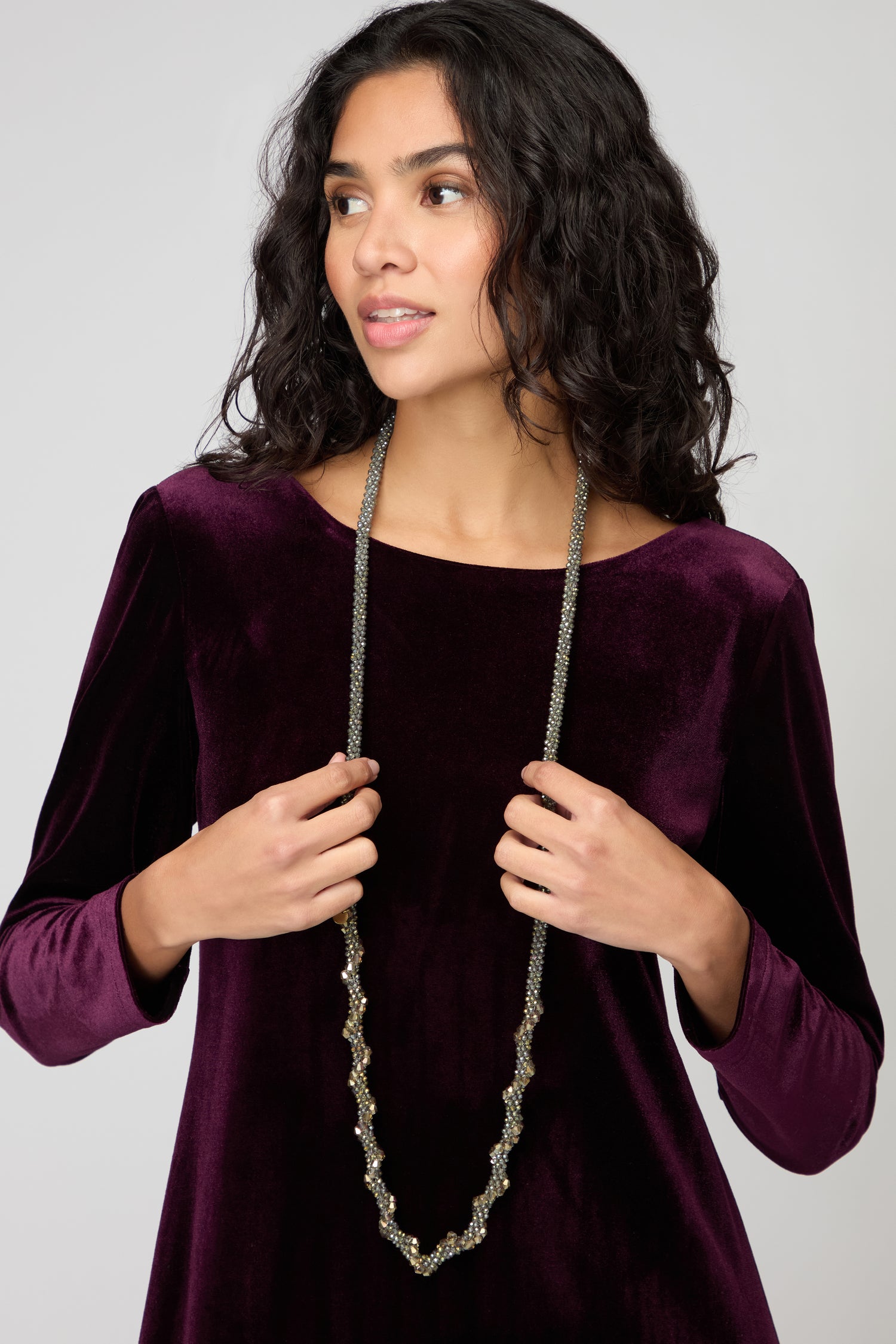Woman wearing the Glacier Spiral Necklace and a long-sleeve, dark purple velvet top, standing against a neutral background.