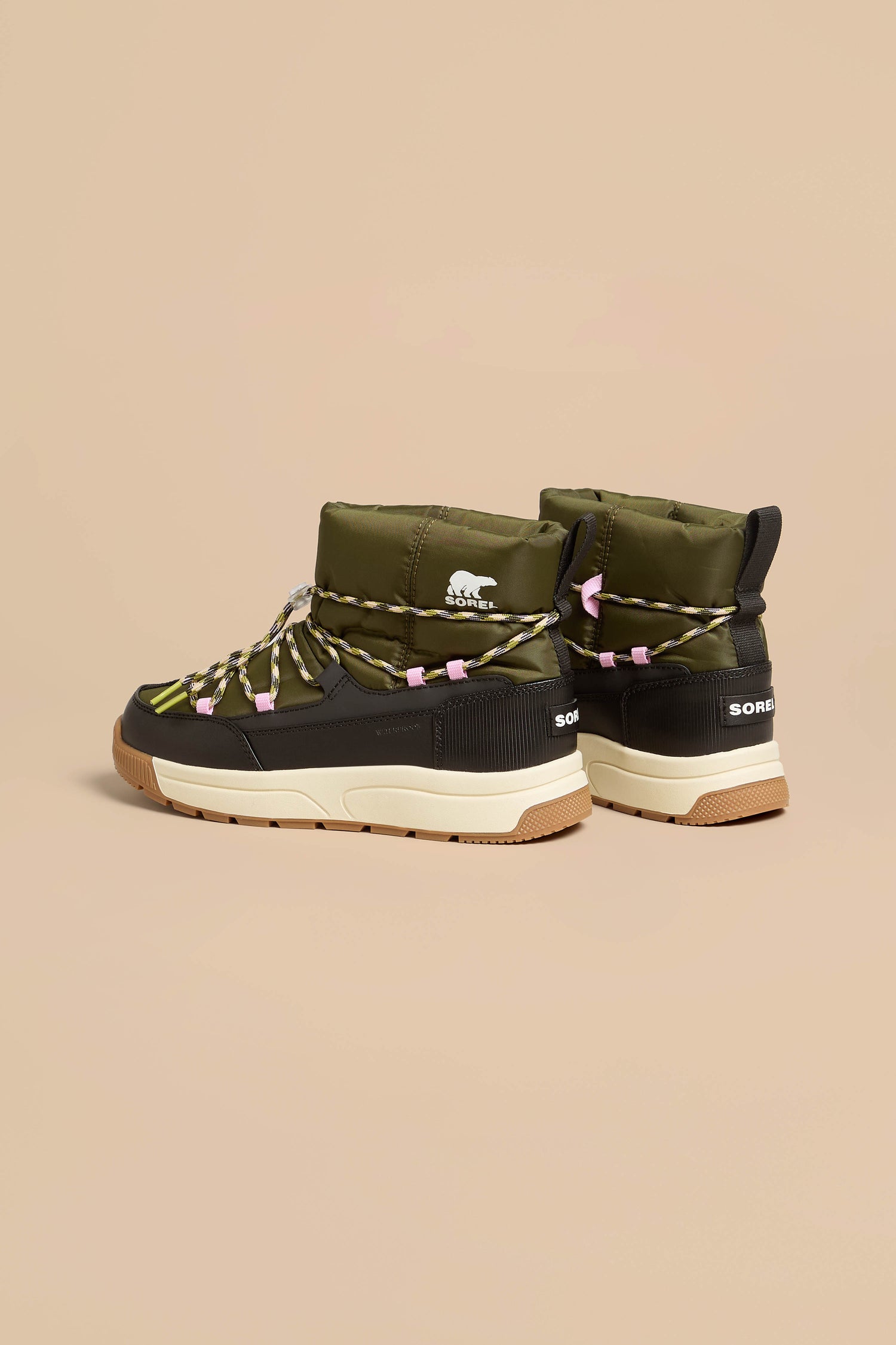 Whitney Quilted Toggle Slip on Boots featuring olive green and black quilted insulation, yellow-patterned laces, pink toggles, and tan rubber soles.