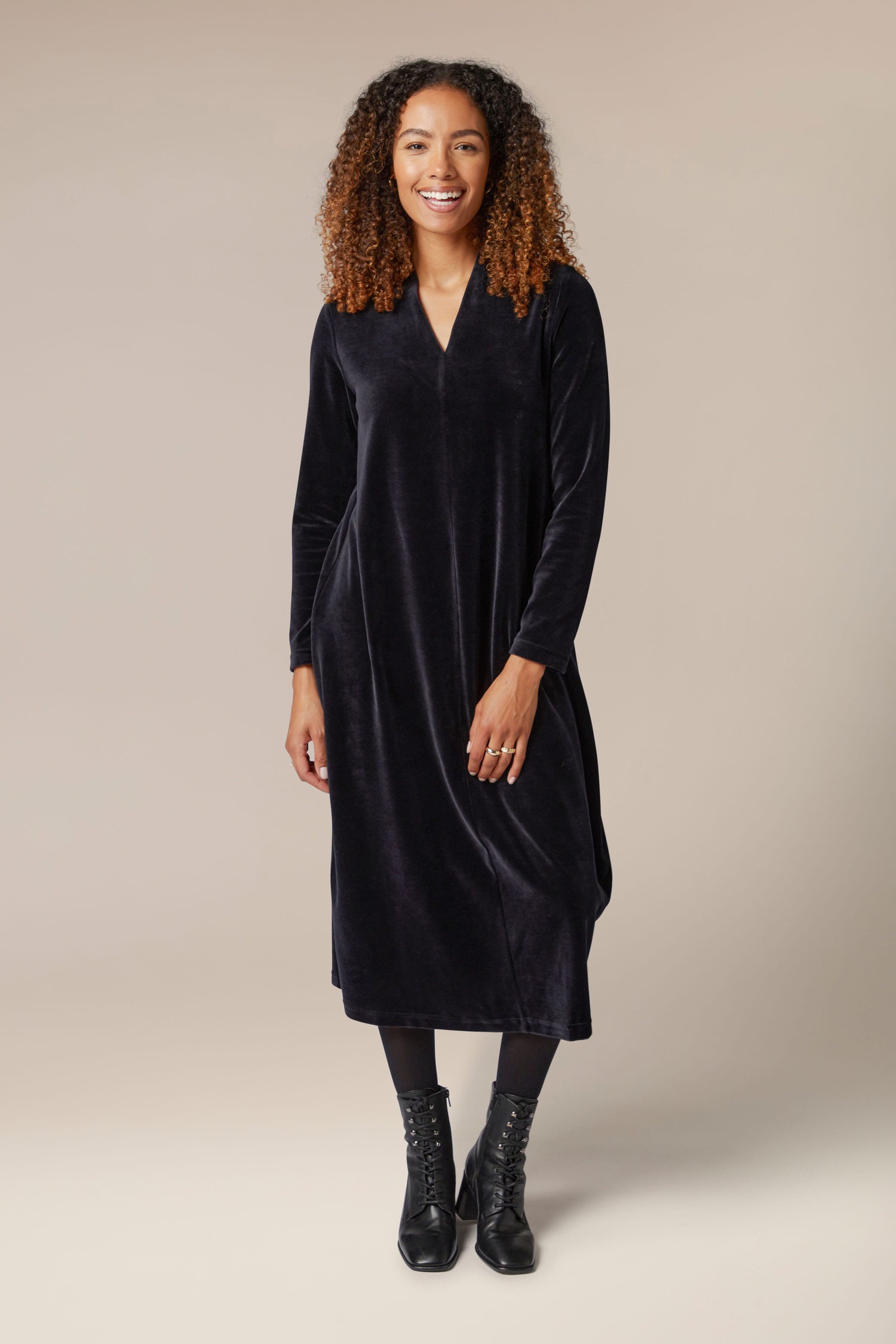 A woman wearing a Velvet Jersey V Neck Dress and black boots.