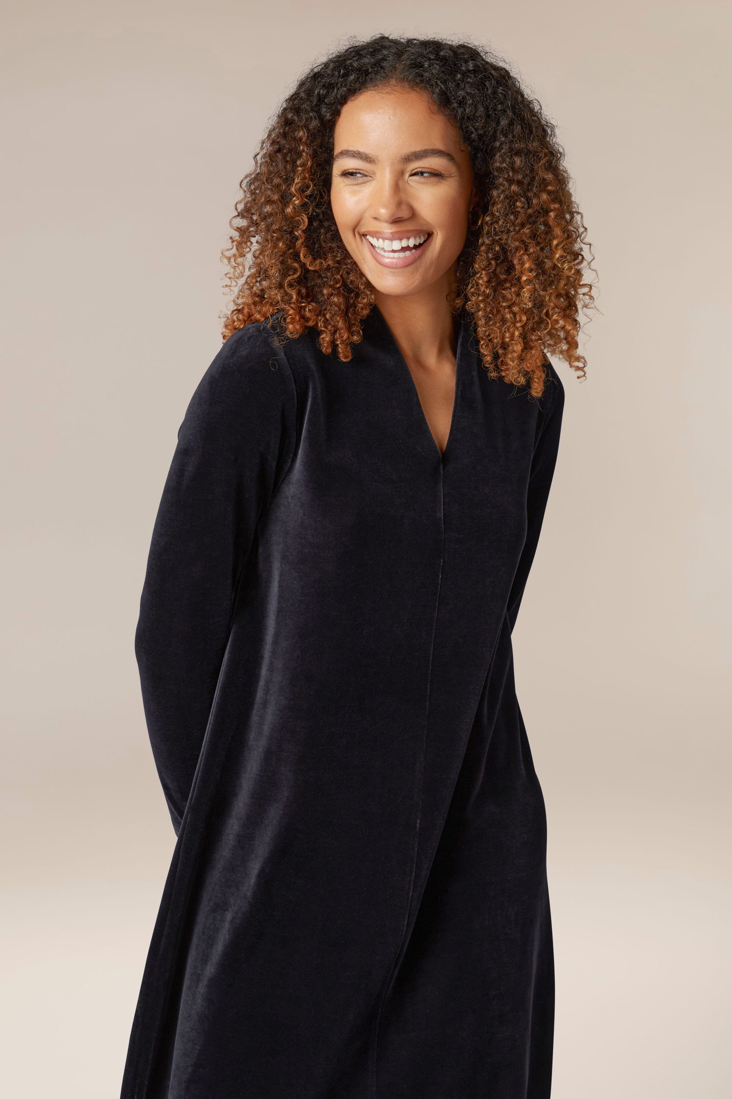 A woman wearing a luxurious black Velvet Jersey V Neck Dress.