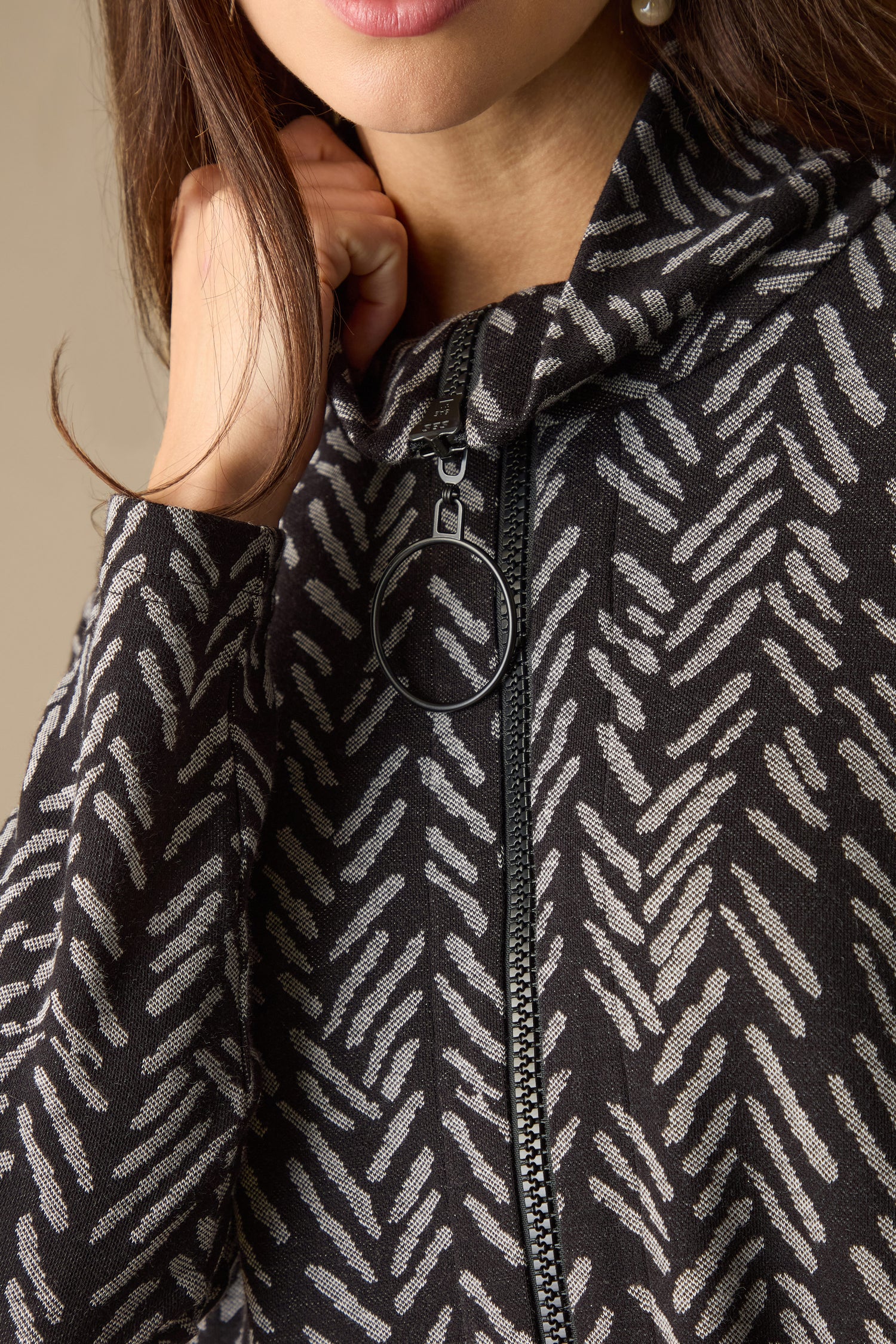 Close-up of a person wearing a Herringbone Jersey Jacquard Dress, featuring a patterned design with a circular zipper pull.
