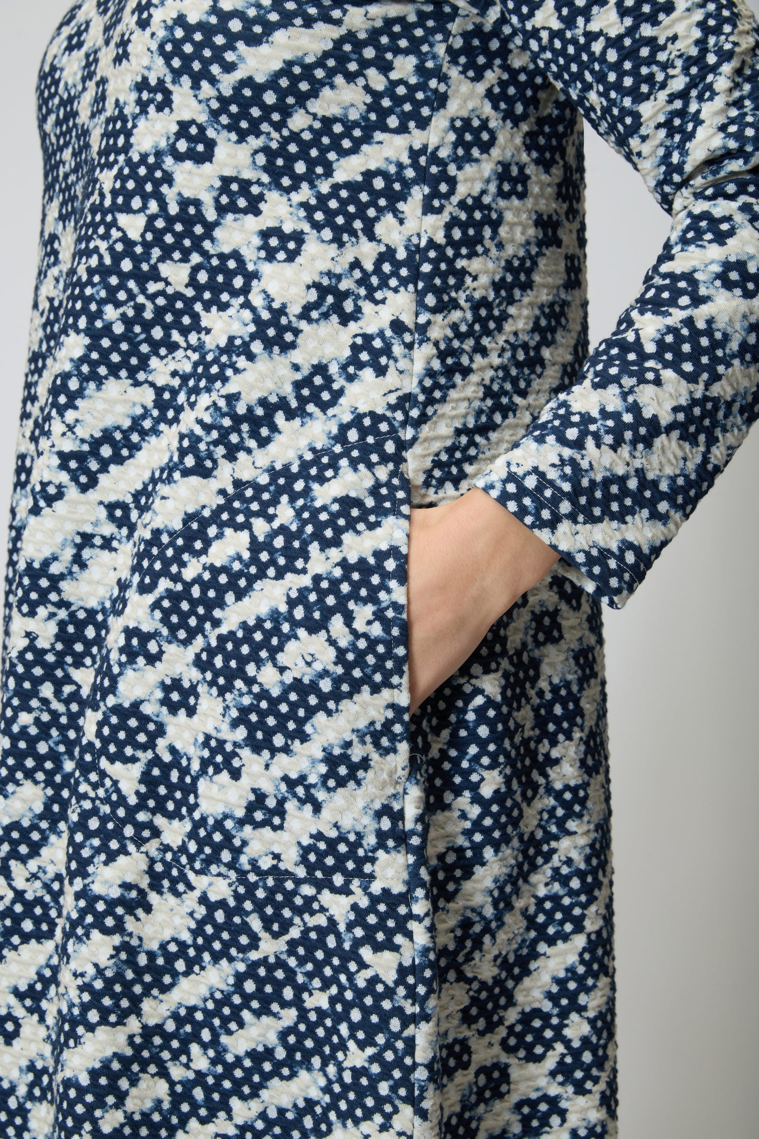 Wearing the Diamond Tie Dye Jersey Bubble Dress in blue and white, a person stands with their right hand tucked into the pocket.