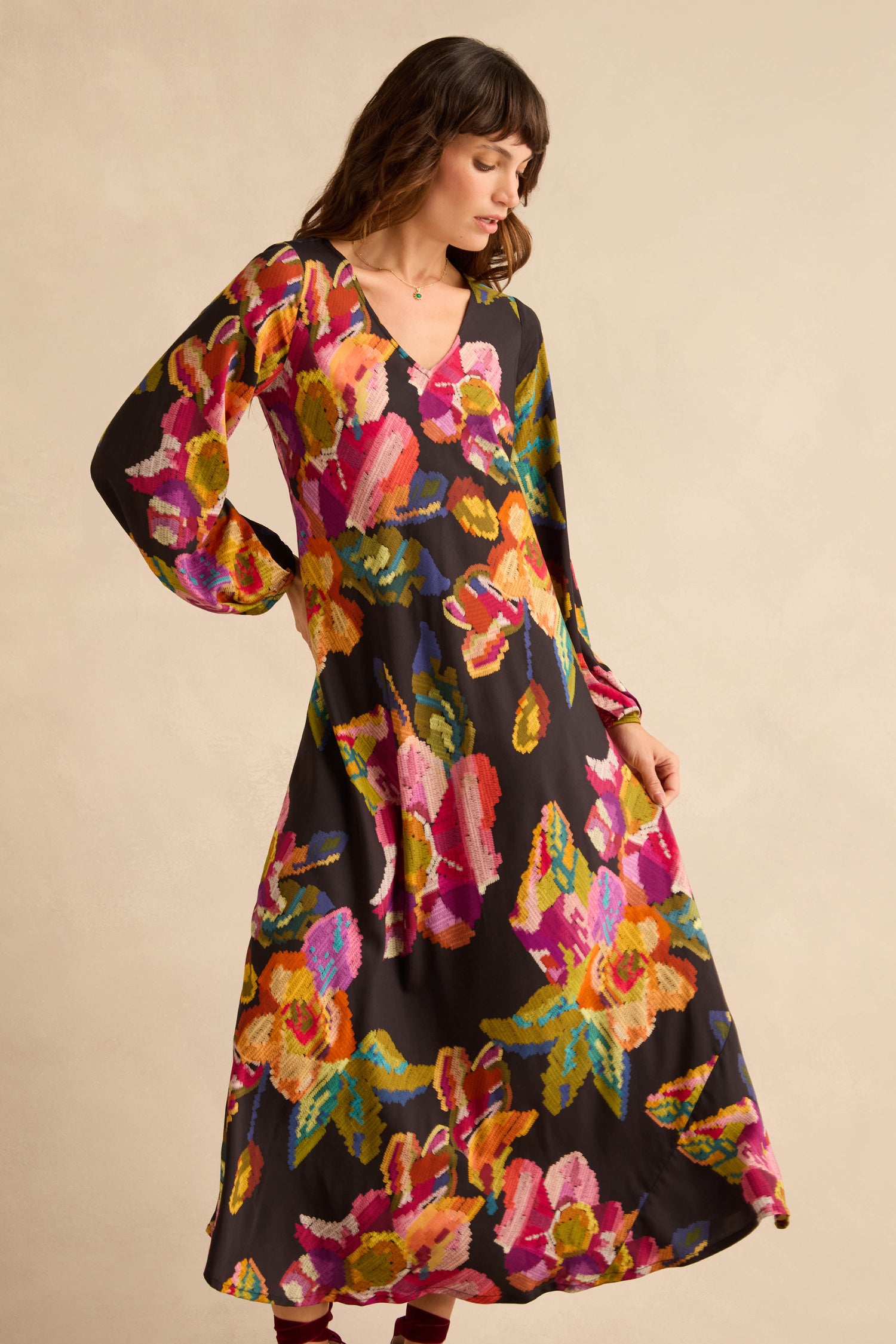 A woman wearing a black, long-sleeved, floor-length Pixelated Floral Flared Dress.