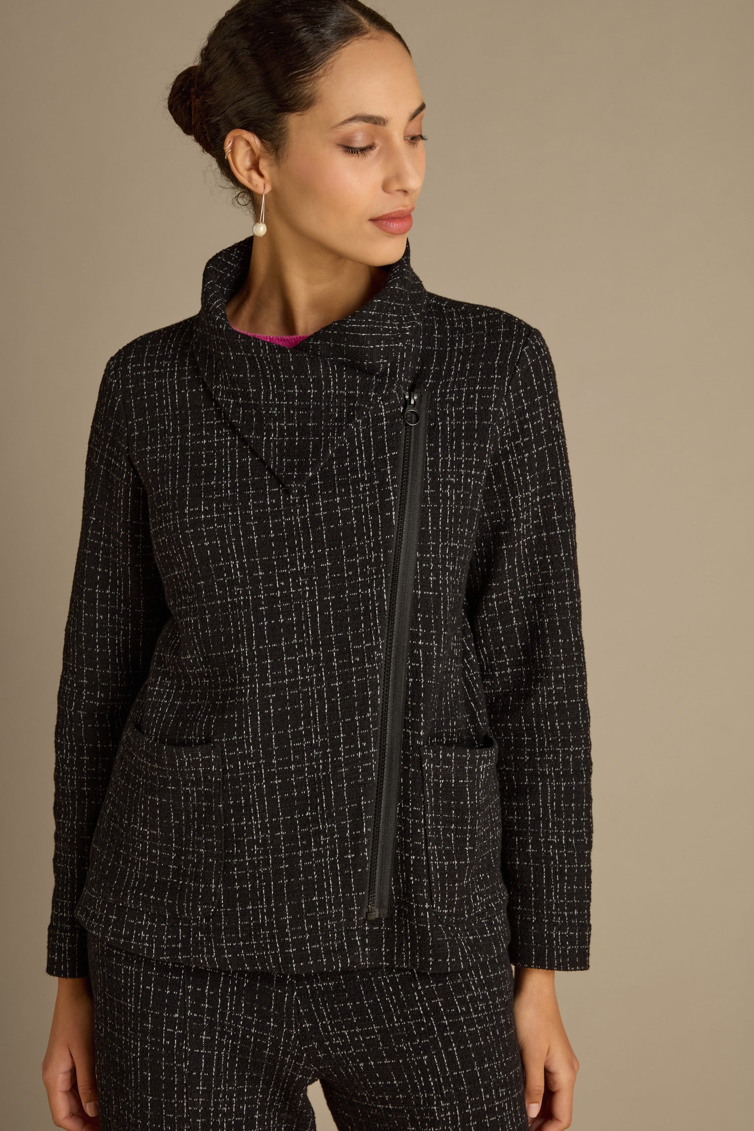 A person wearing the Boucle Cotton Jersey Zip Jacket, featuring a black and white pattern and an asymmetrical zipper that exudes a classic biker silhouette, stands against a neutral background.