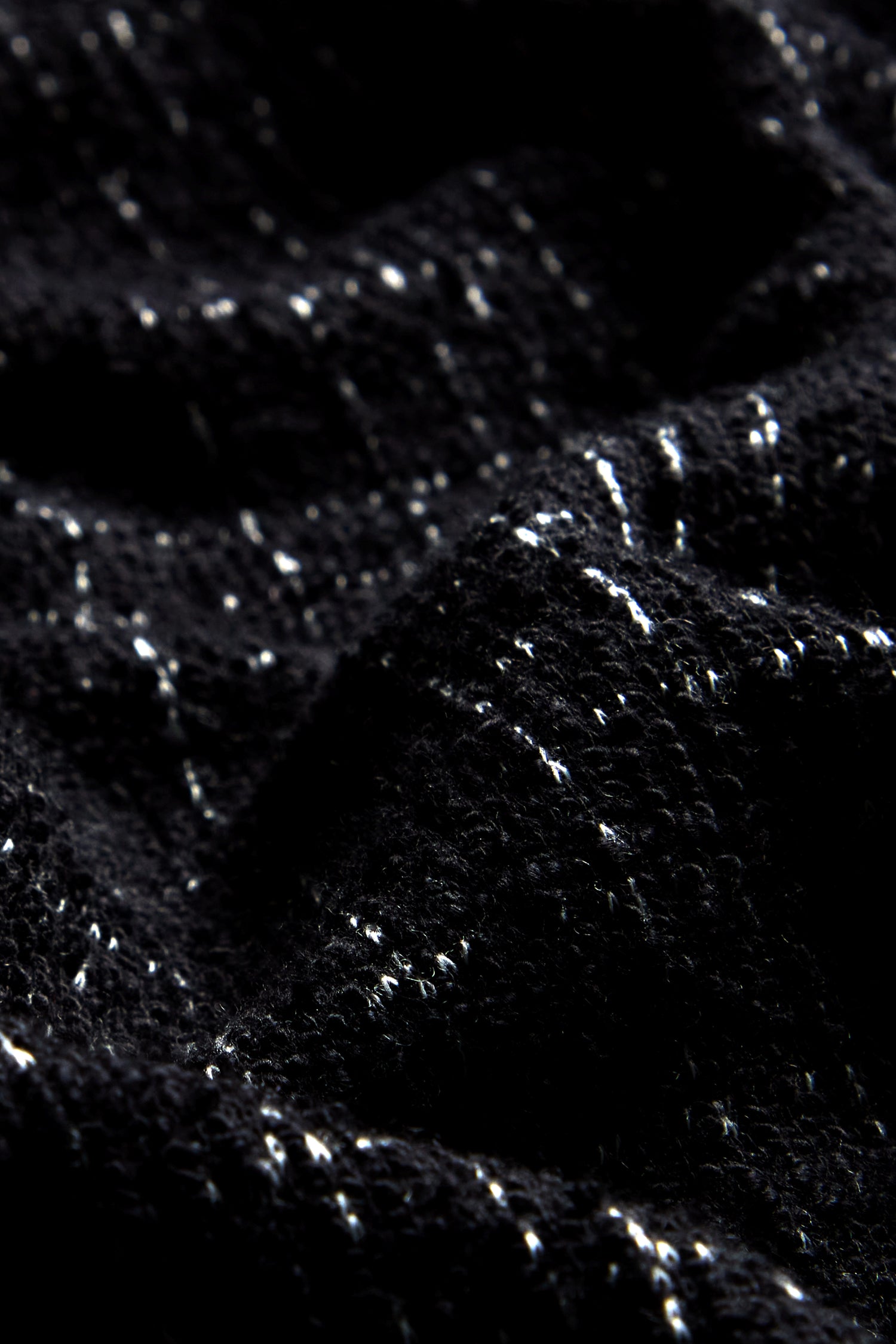 Close-up of the fabric from the Boucle Cotton Jersey Zip Jacket in black with white speckles, showcasing a wavy pattern that evokes a biker silhouette.