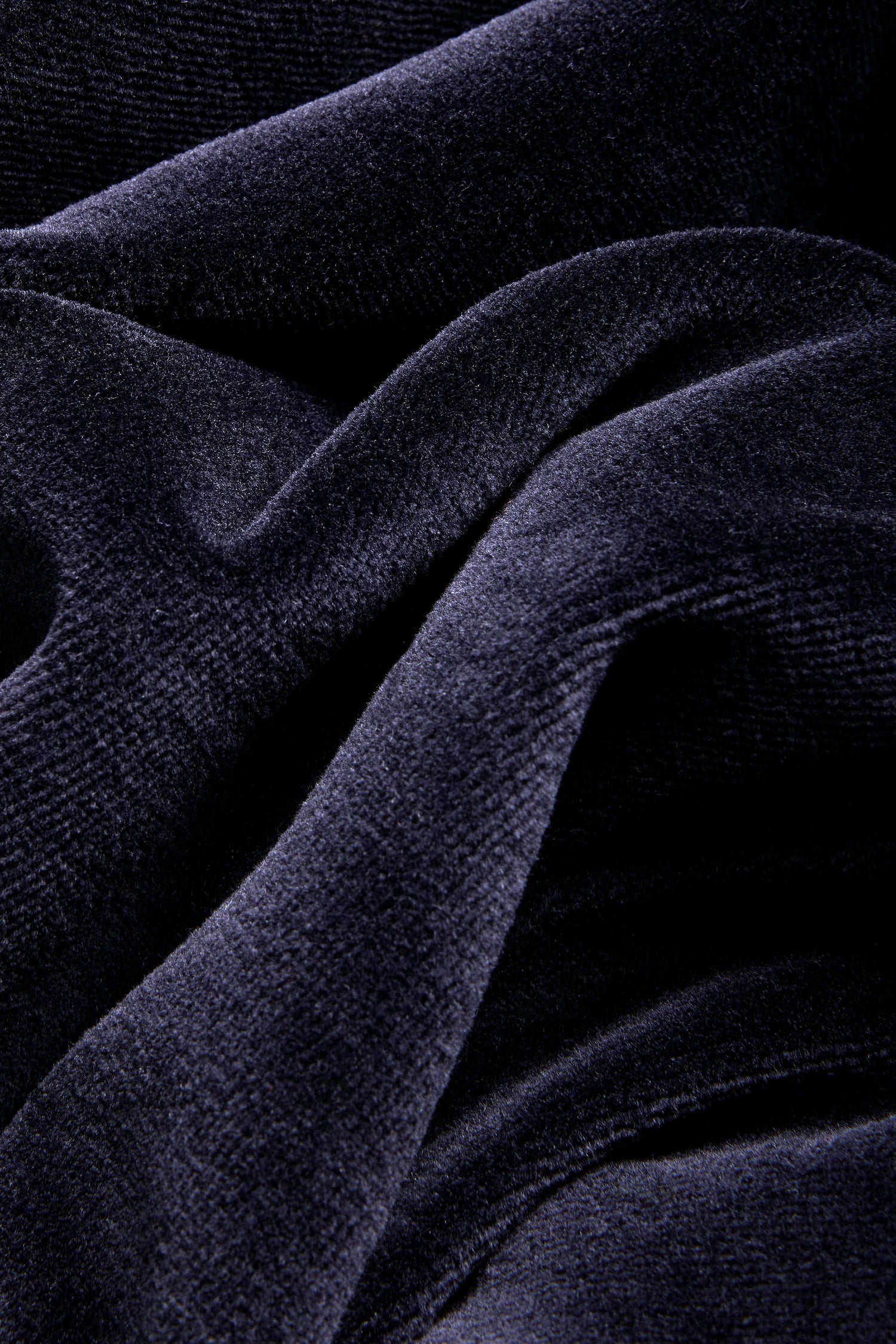 Close-up of navy blue velvet fabric with soft folds and a textured surface, highlighting its smooth and plush appearance—the ideal material for crafting the elegant Night Velvet Jersey Bubble Trousers made in England.