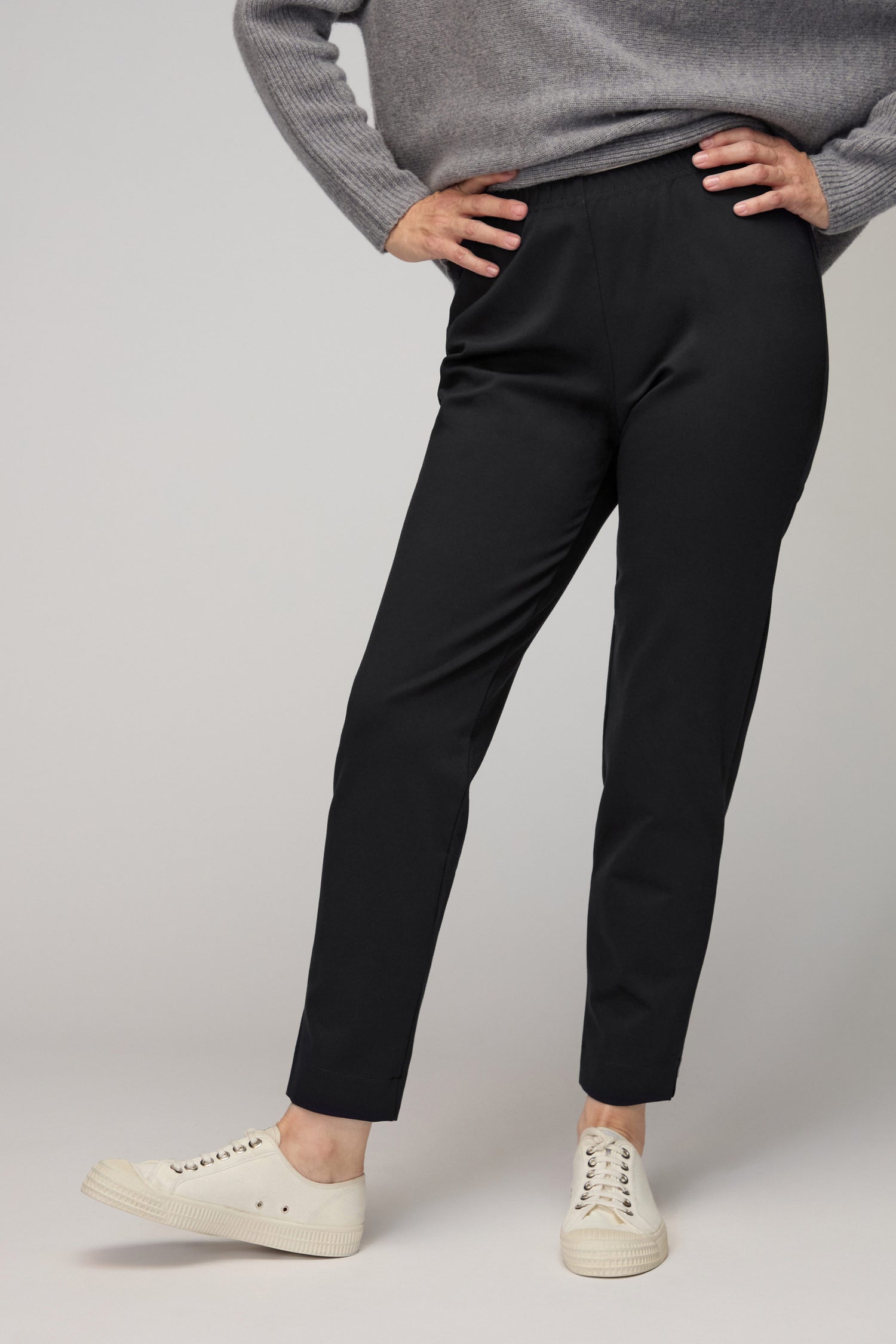A person models the Ponte Slim Leg Trousers with a grey sweater and white sneakers, standing confidently against a simple backdrop—highlighting this versatile wardrobe staple.