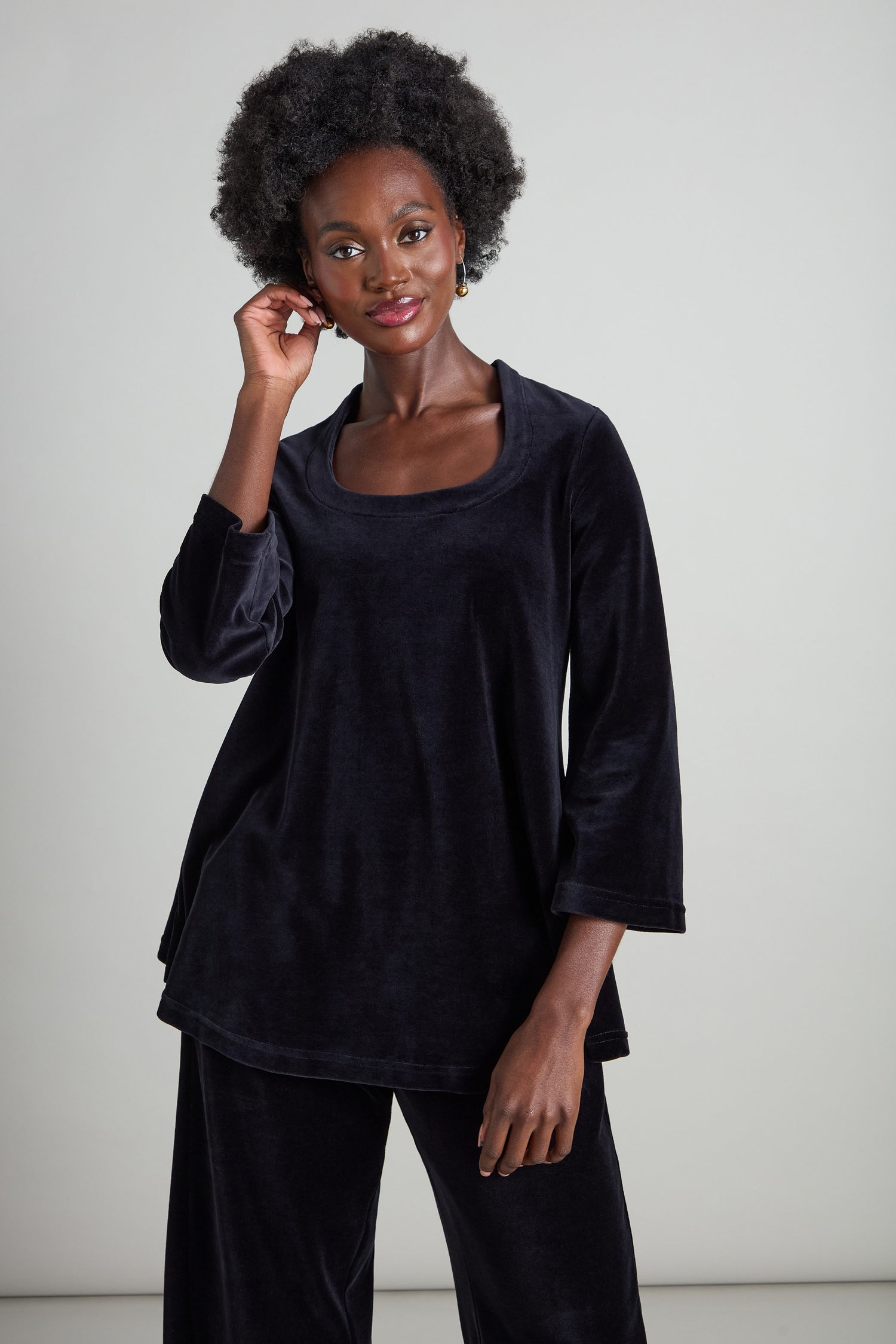 A person wearing a Velvet Jersey Horseshoe Neck Top with flared sleeves poses against a plain background.