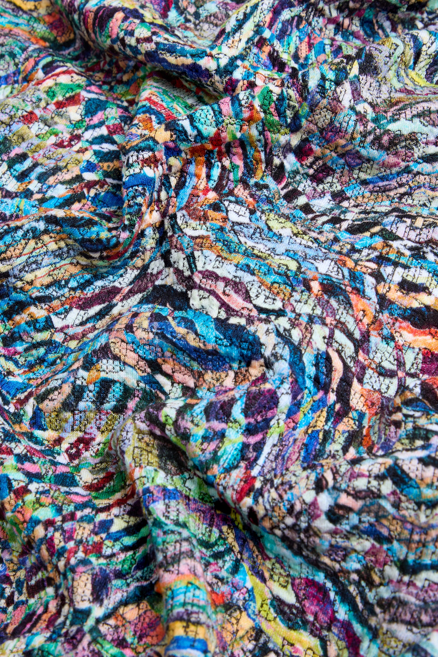 Close-up of the Patchwork Fields Jersey Top, a colorful and textured piece with an abstract, multicolored pattern of overlapping lines and swirls; this top features a boxy silhouette and is made in England.