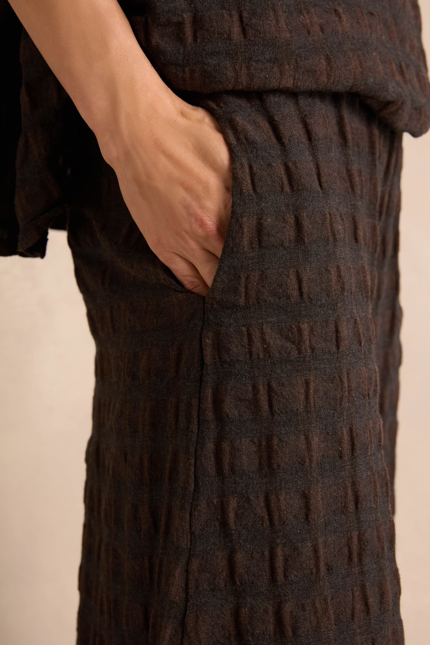 A hand is placed inside the pocket of Chocolate Waffle Check Wide Trousers.