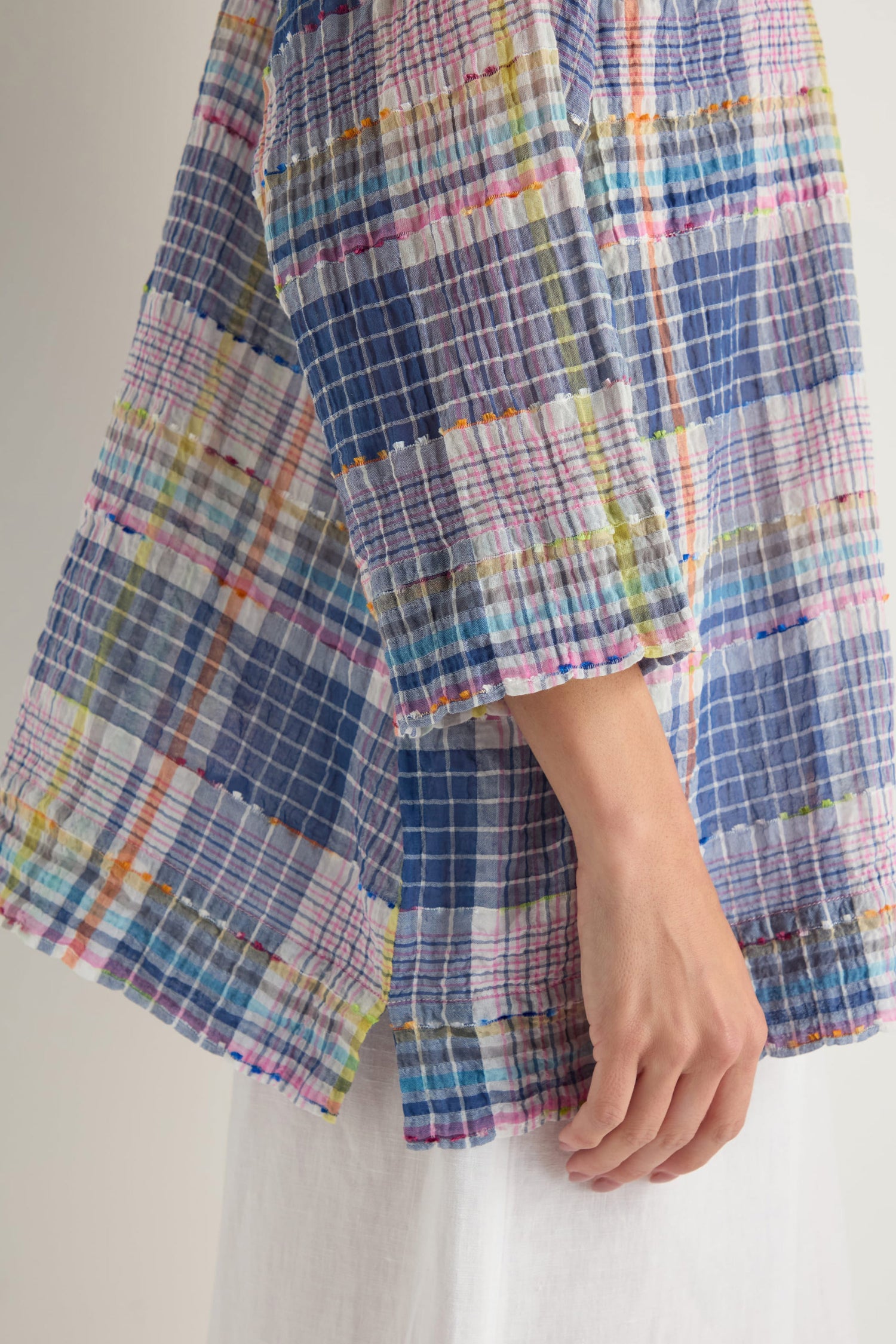 A person shown from the side wears the Crinkle Check Jacquard Shirt in blue with a boxy fit, paired with white pants.