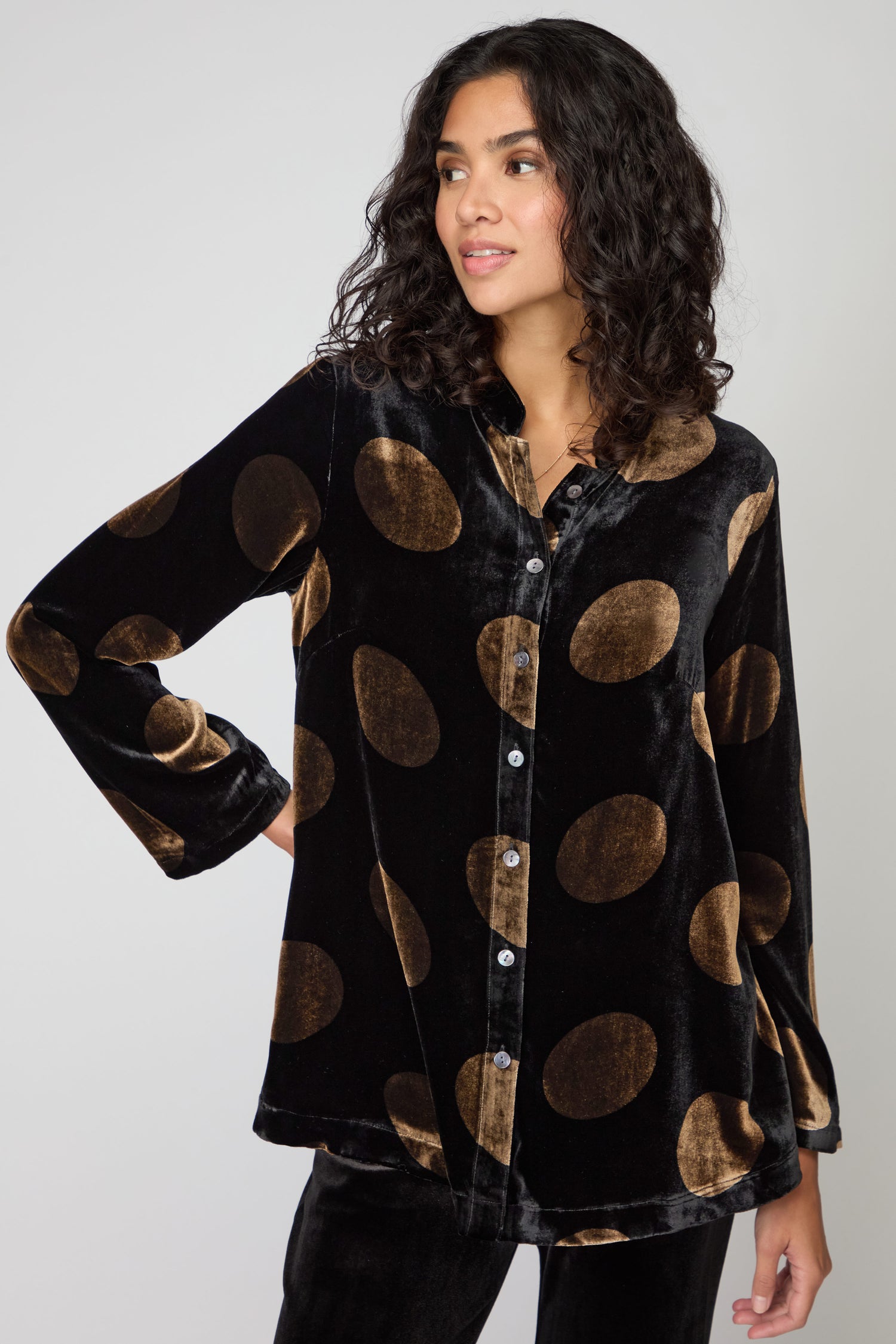 Someone models the Silk Velvet Spot Shirt, a black silk velvet top with large gold spots, paired with matching pants, standing against a plain background.