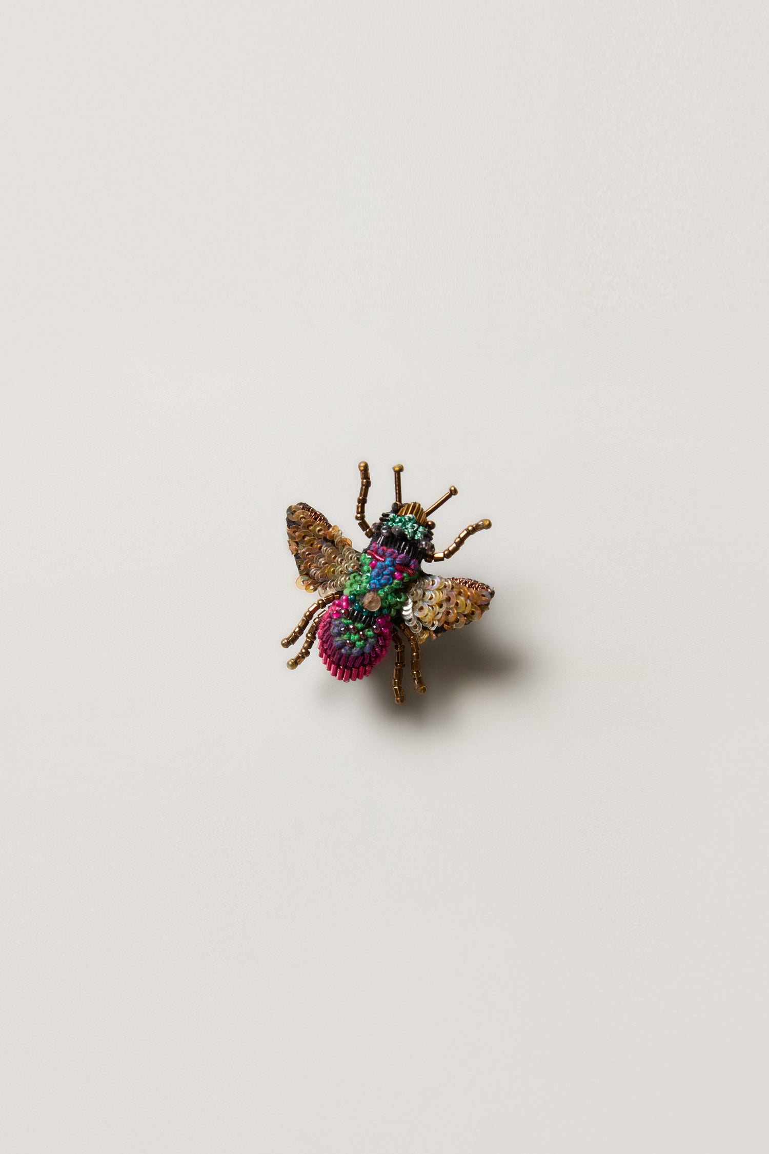 The Hand Beaded Sequin Rainbow Bee Brooch features multicolored beads and sequins forming a decorative bee shape, displayed on a plain white background.
