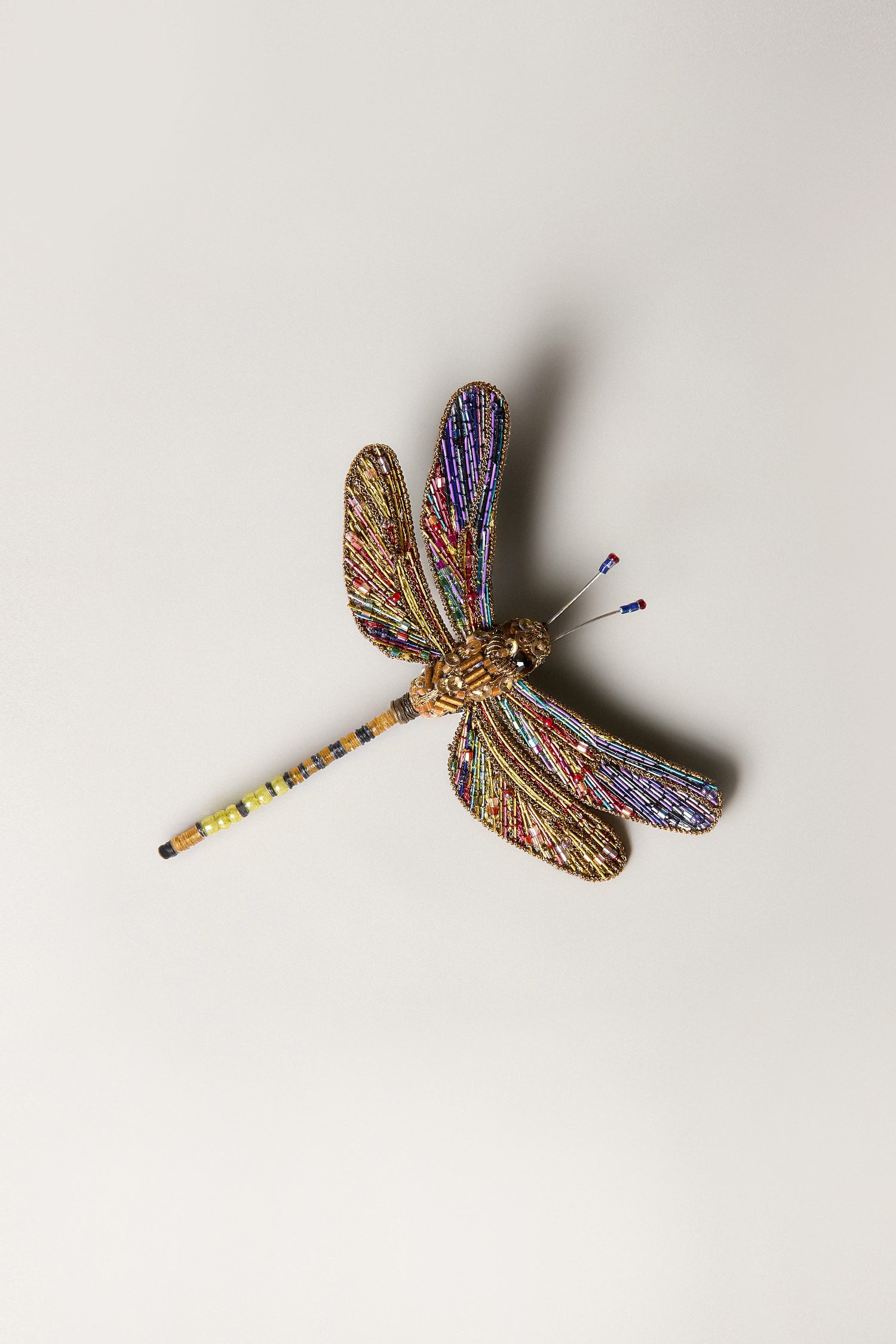 The Hand Beaded Hawker Dragonfly Brooch, made with colorful beads and wire, is showcased against a plain light background—an exquisite example of wearable art.