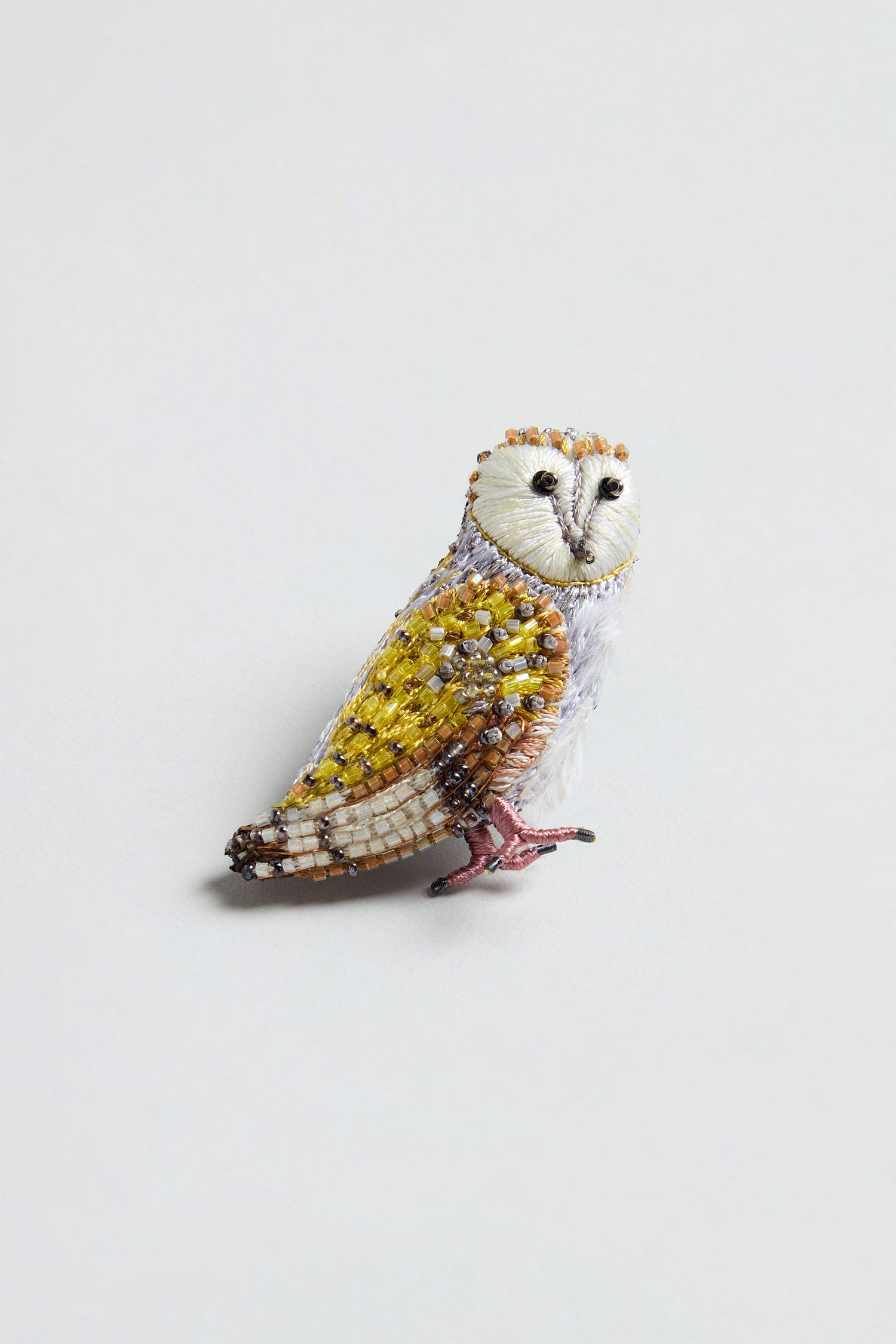 The Hand Beaded Gold Owl Brooch features white, yellow, and brown beads with detailed wings and a black-eyed face, set against a plain light background.