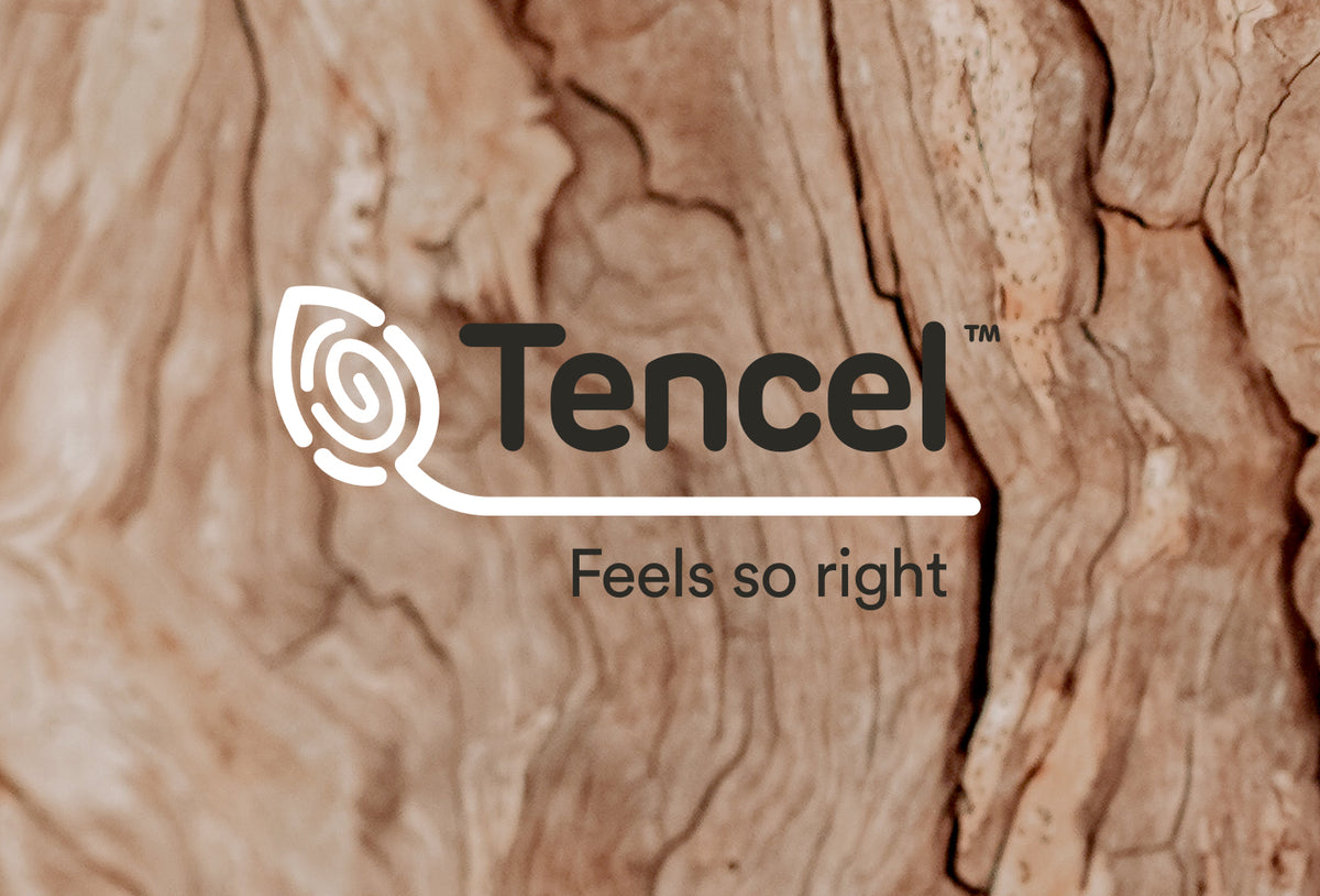 A image of brown textured wood background with "Tencel™" logo and tagline "Feels so right" in black with a white icon running through the words.