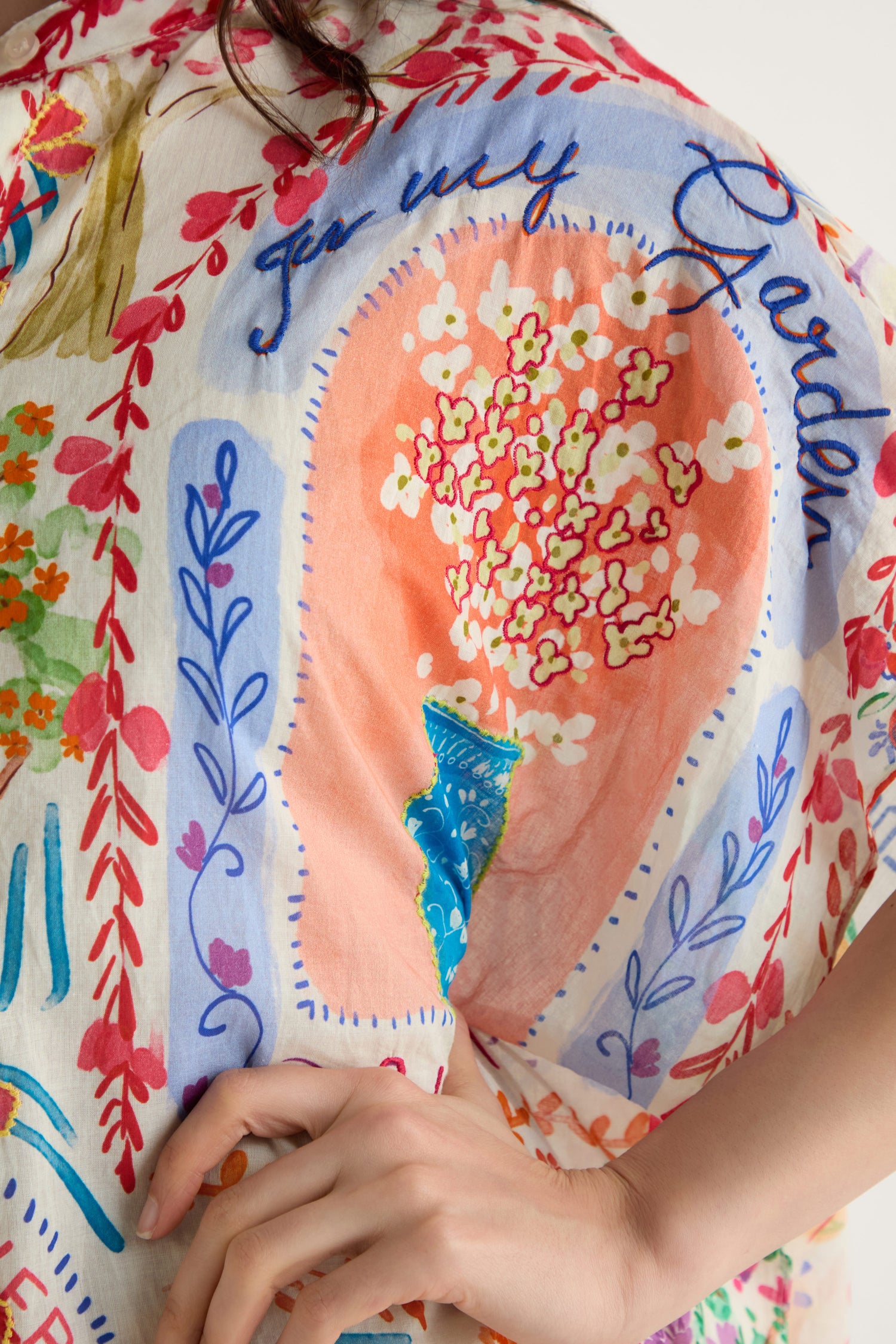 A close-up of a person’s shoulder wearing the Floral Bouquet Cotton Shirt Dress, featuring a colorful floral bouquet print and handwritten text that includes the words "for my Garden.