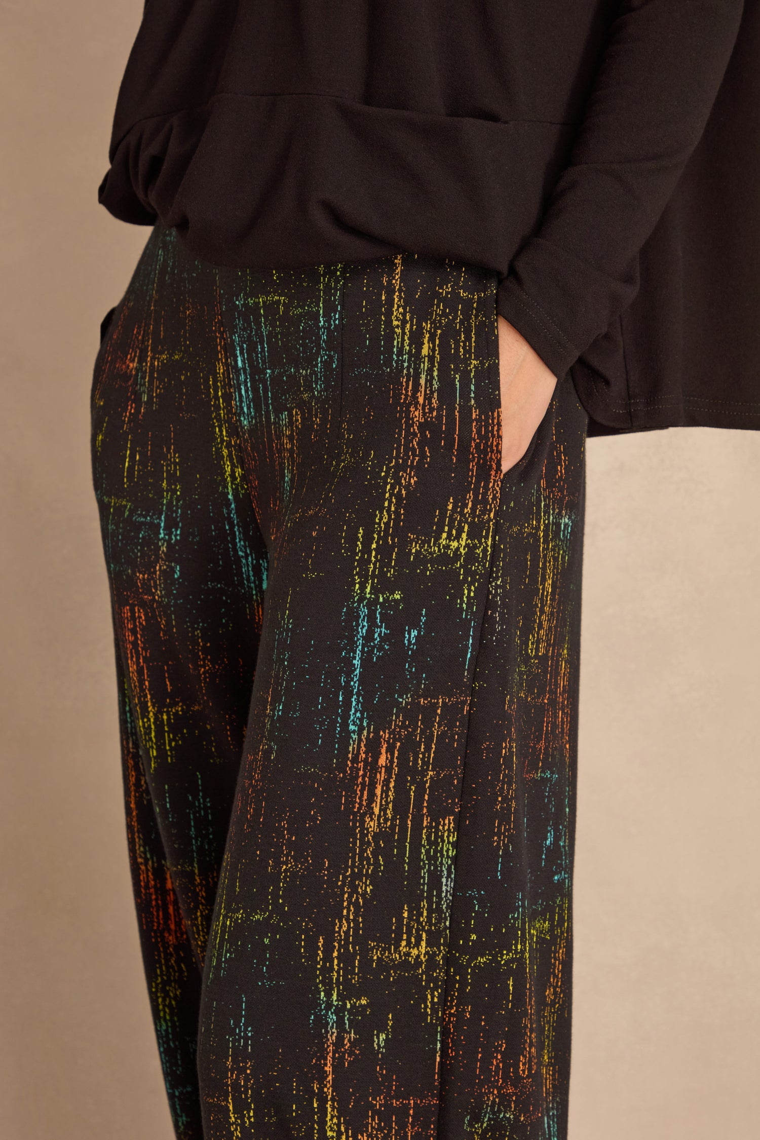 Person shown from waist to mid-thigh wears Space Dye Jacquard Bubble Trousers with a black long-sleeve top, one hand in the pocket, against a neutral background.