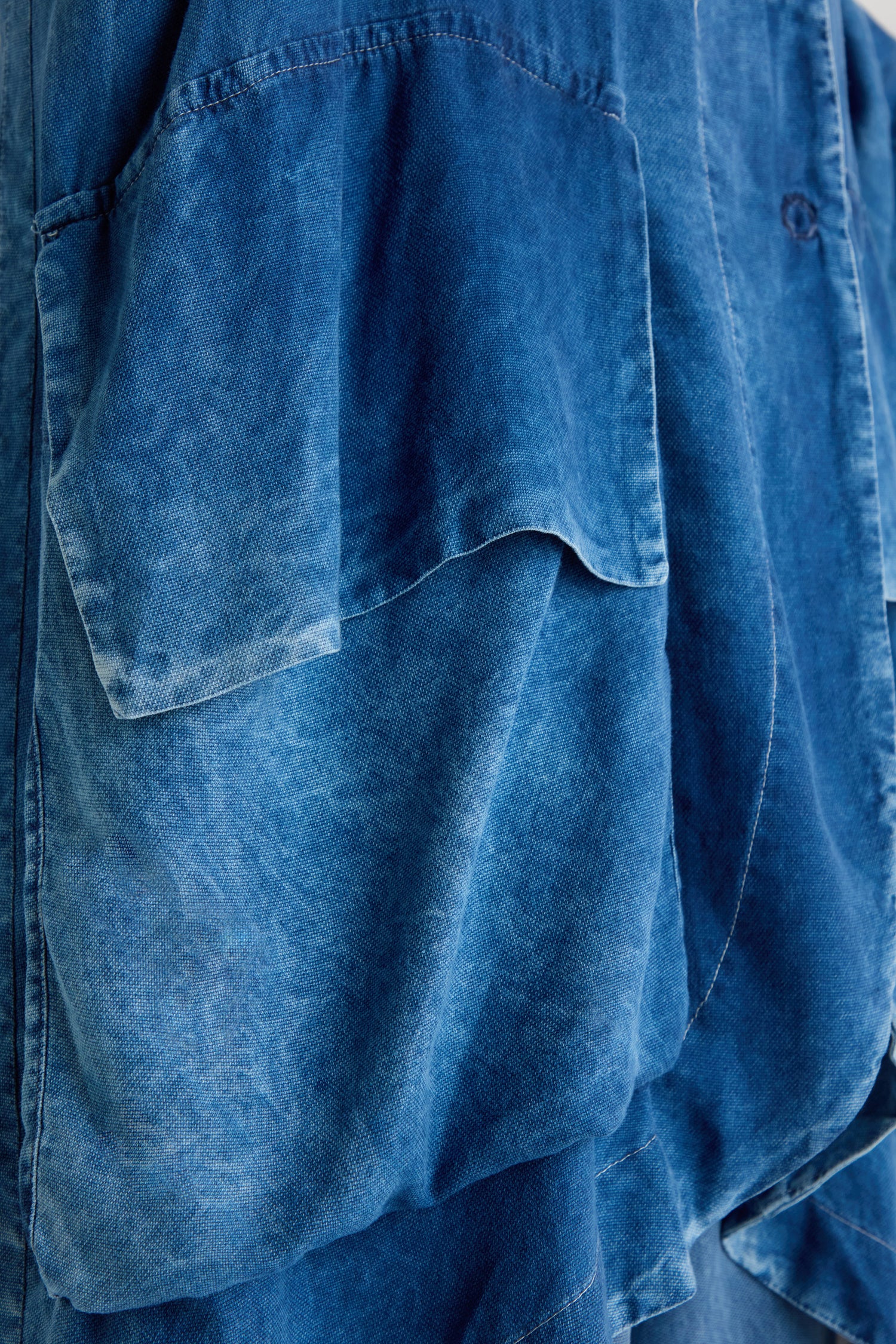 Close-up of the Lyocell Utility Jacket in blue, showcasing its relaxed silhouette, large pocket, visible seams, and a washed finish.
