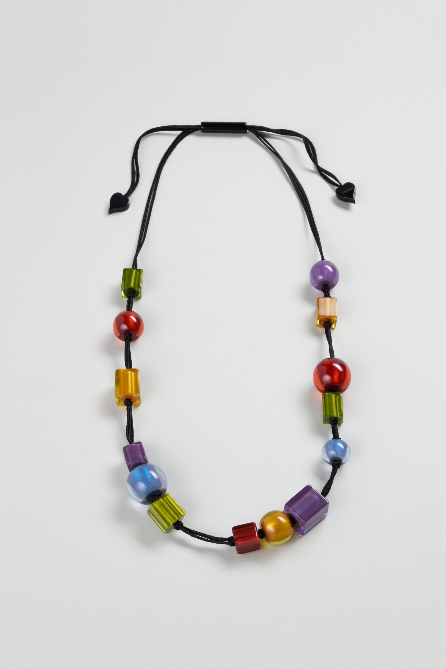 The Colourful Shapes Resin Necklace features a black cord with assorted geometric resin beads in red, blue, green, purple, and gold—an eye-catching handmade piece shown against a plain white background.