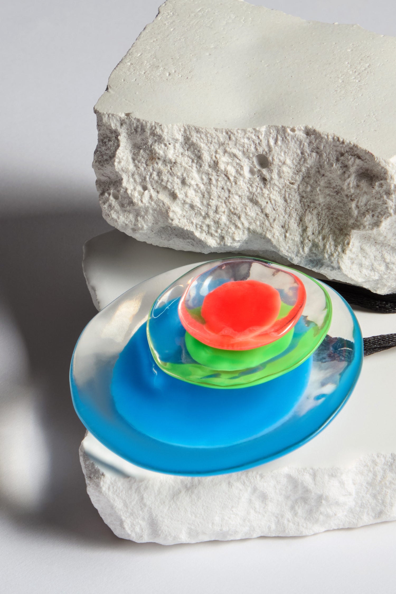 Part of the FLORA collection, the Blue Neon Flora Pendant is a colorful glass sculpture with red, green, and blue elements on white textured stone and features a handcrafted resin pendant for added charm.