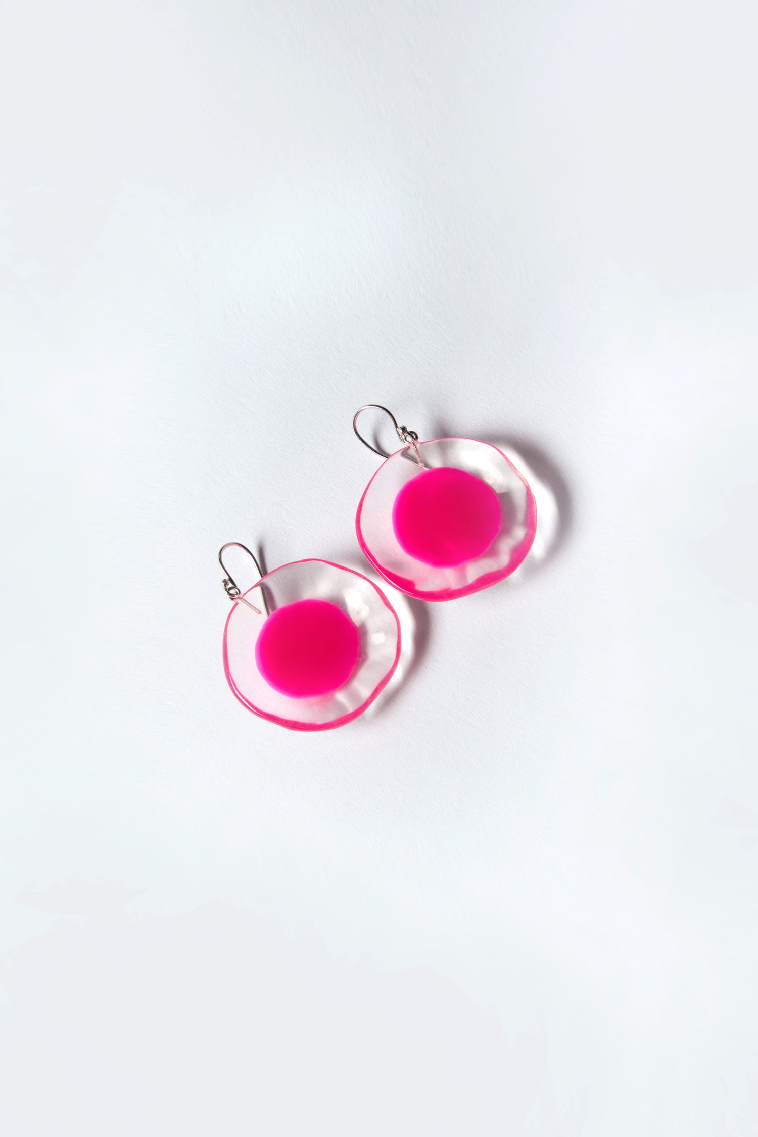 The Flora Earrings by Prue by Zsiska feature two circular resin pieces with elegant pink centers and translucent pink edges, designed against a white background.