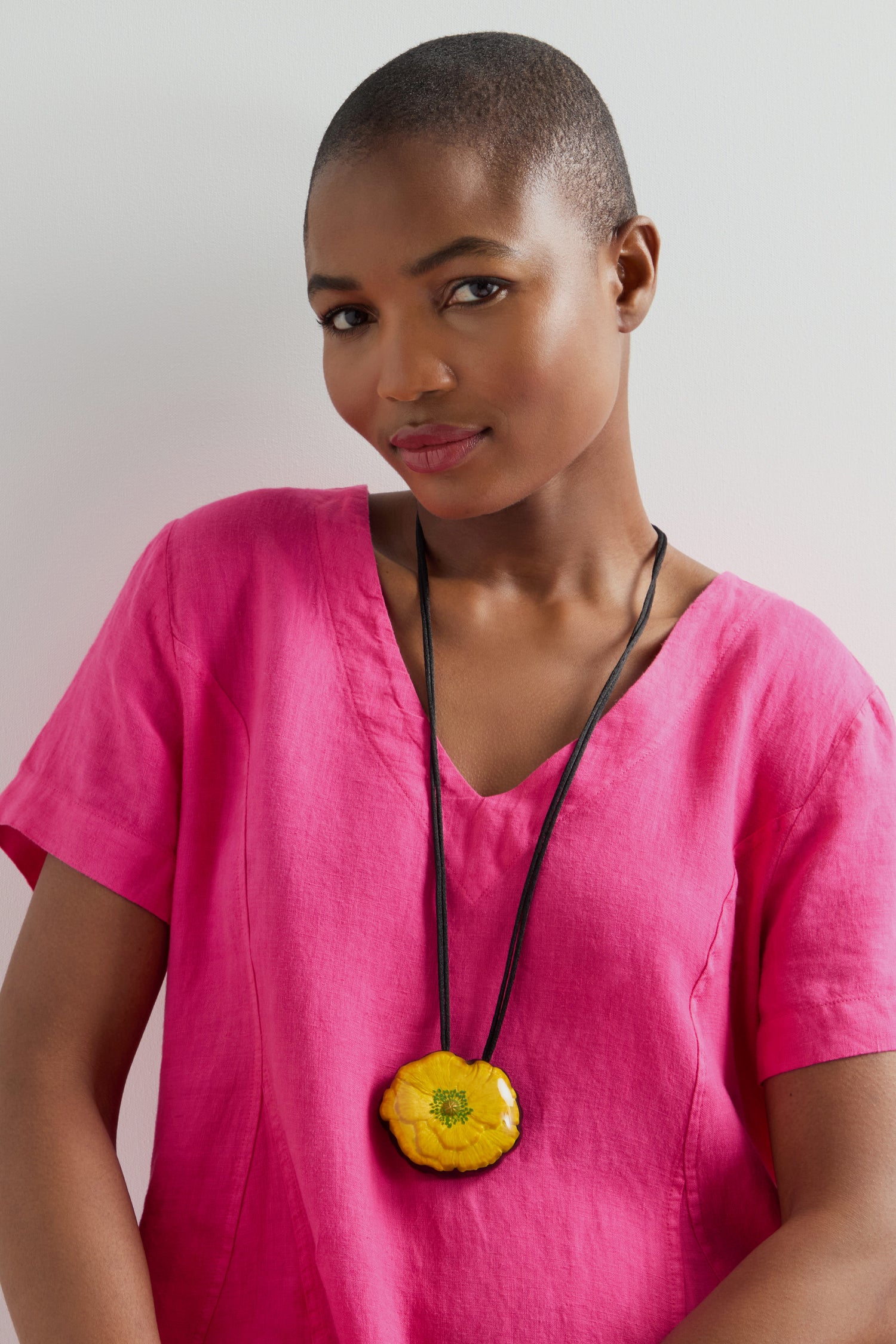 Person wearing a necklace featuring the Garland Pendant stands against a white background in a pink shirt.