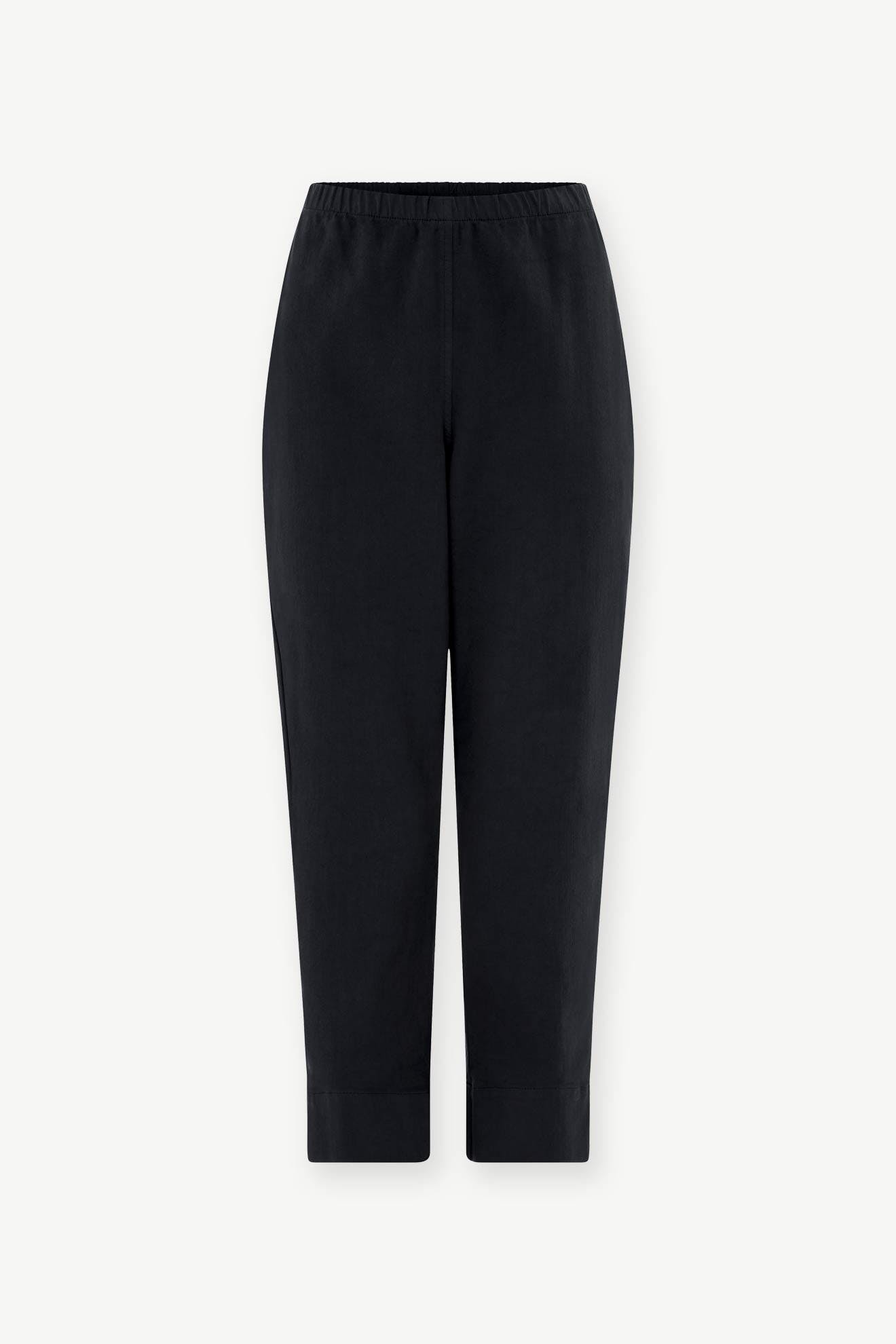 The SS22 Stretch Cotton Trouser features a black slim-leg tapered fit, elasticated waist, cropped length, and a minimalist design, shown against a plain white background.