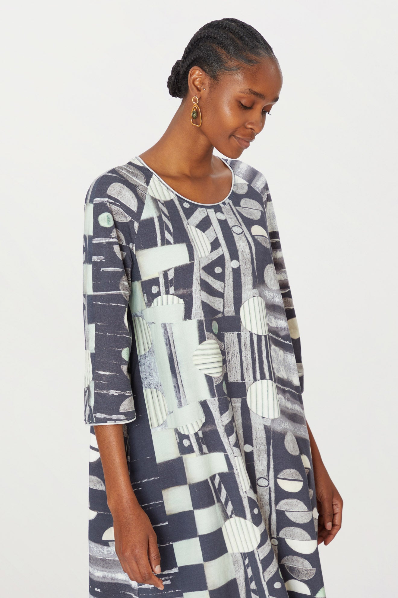 A woman in a Miro jersey dress looks down and to the side, standing against a white background.