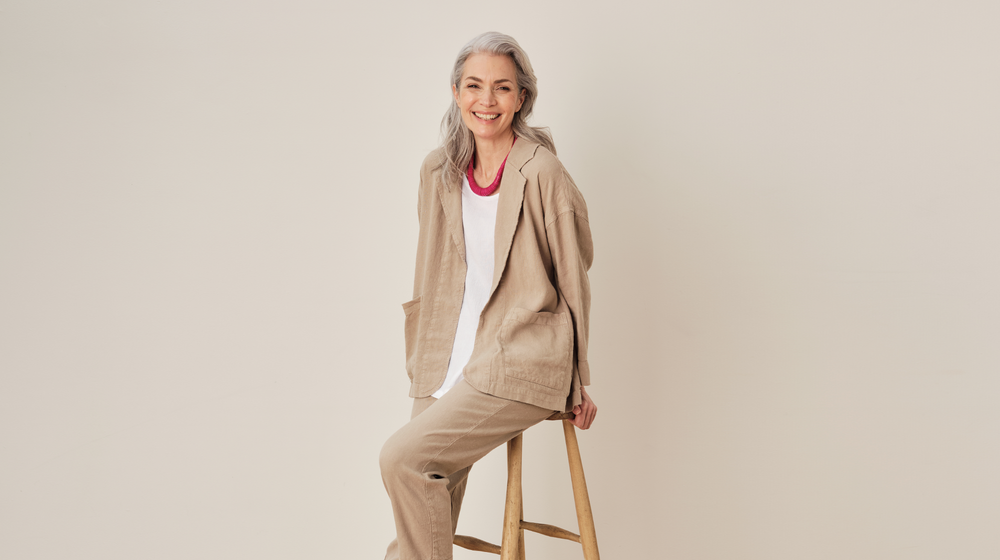 An elderly woman sitting on a stool.