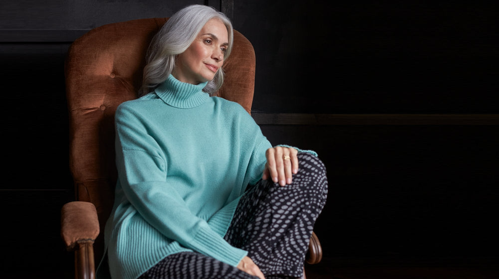 A woman in a turtleneck sweater sitting in a chair.