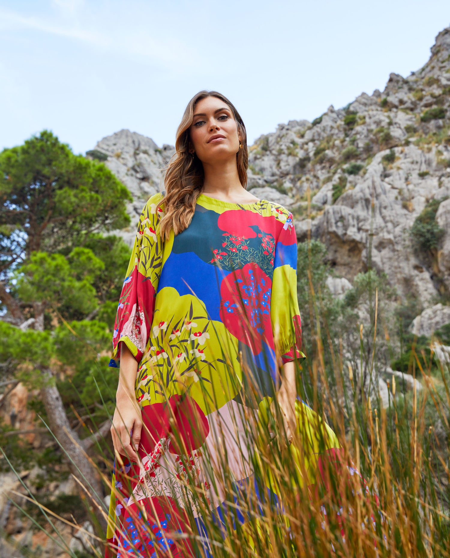 woman in a bright patterned dress stood in front of mountain