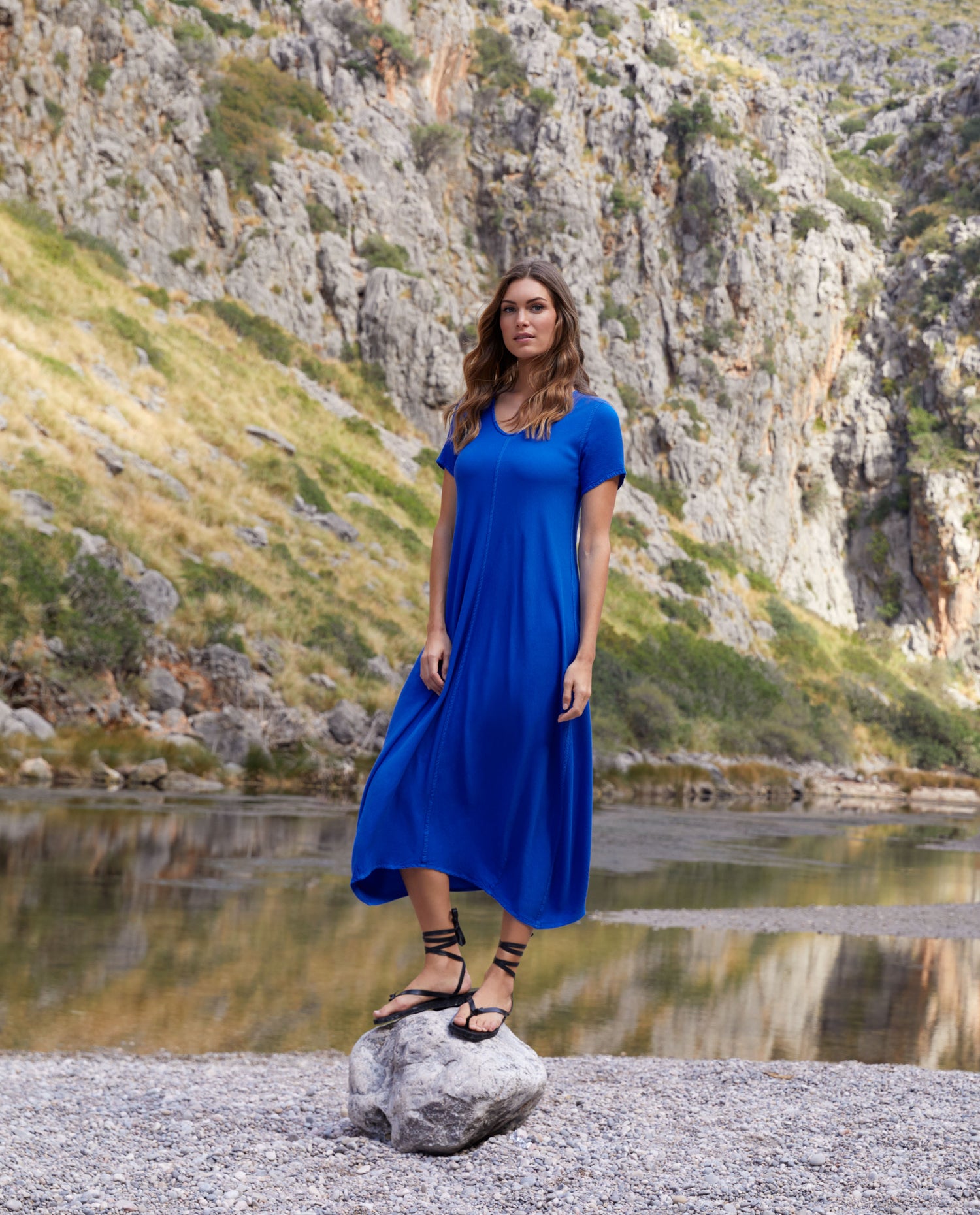 woman wearing a blue long dress stood on a rock