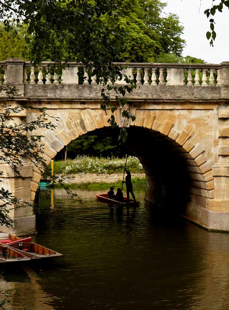 man pushing a boat underneath a bridge
