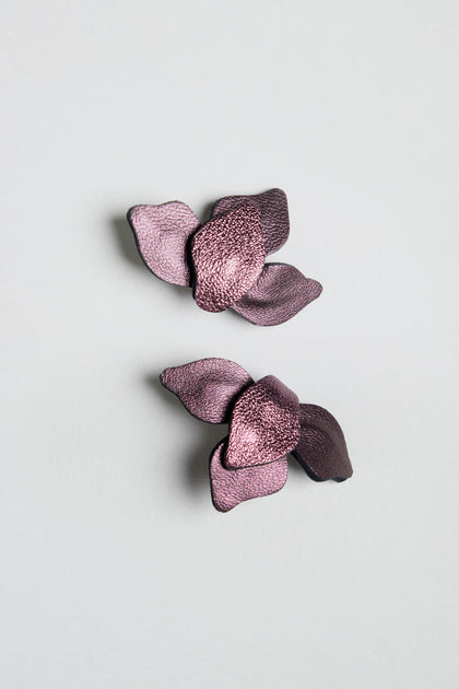 A pair of Metallic Burgundy Leather Petal Earrings are displayed on a plain light gray background.