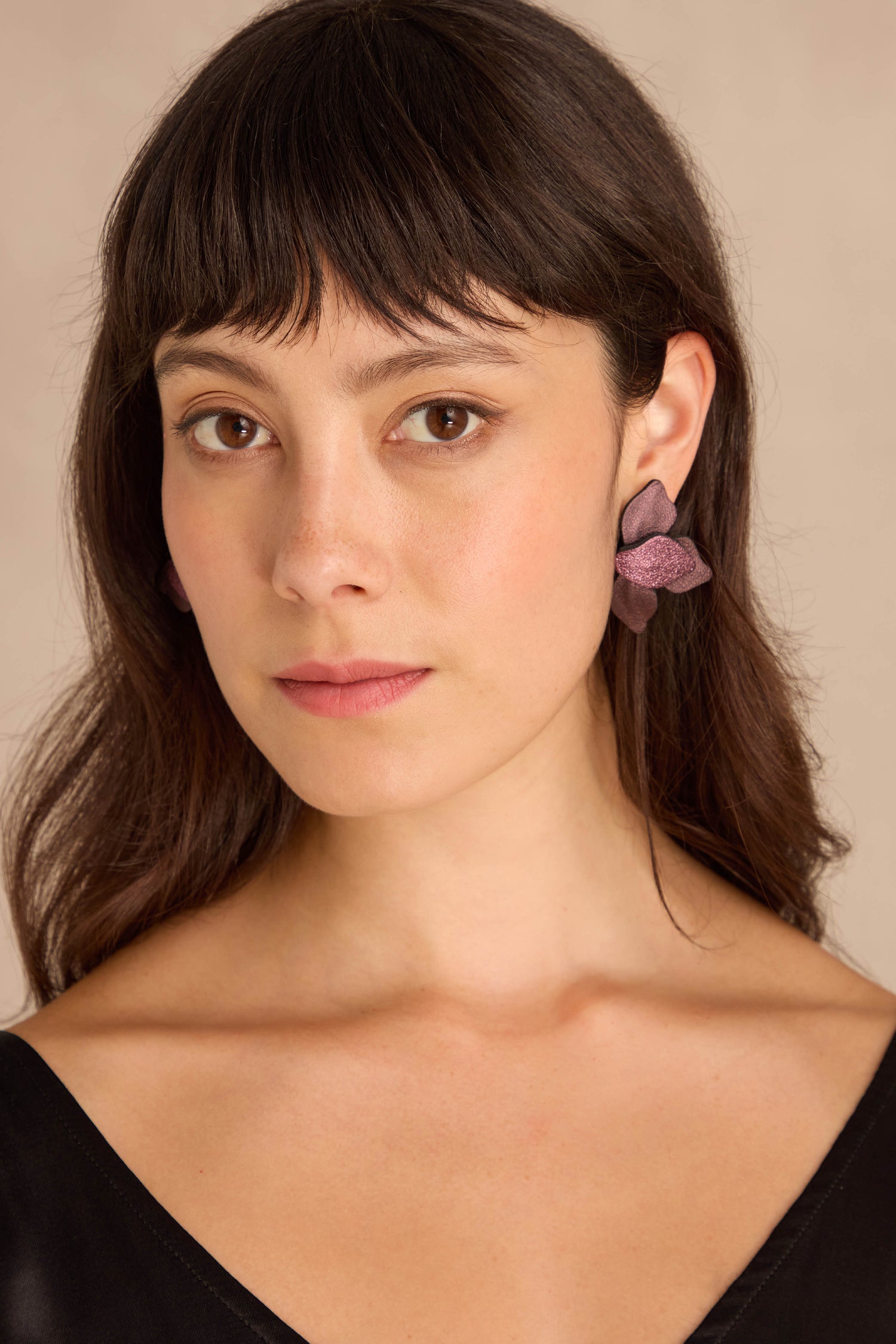 Woman with straight brown hair and bangs wears Metallic Burgundy Leather Petal Earrings and a black top, facing forward against a neutral background.