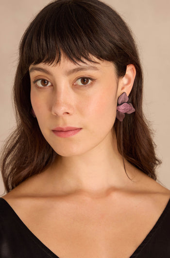 Woman with straight brown hair and bangs wears Metallic Burgundy Leather Petal Earrings and a black top, facing forward against a neutral background.