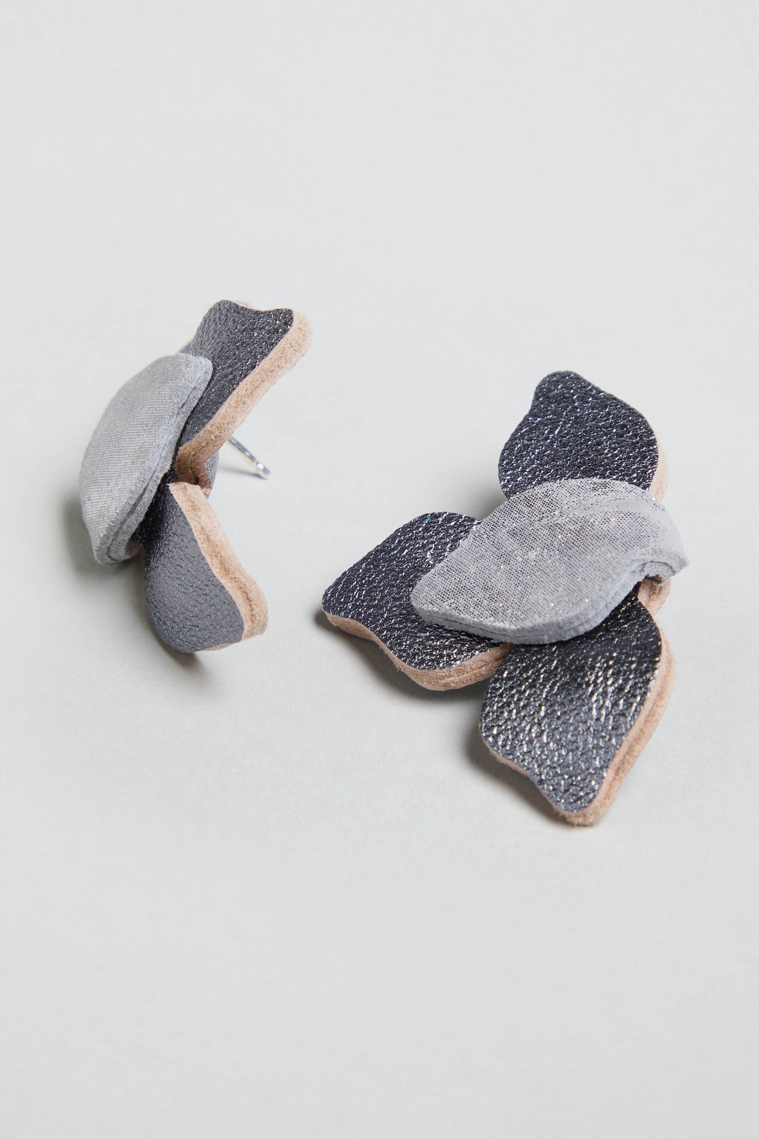 Metallic Grey Leather Petal Earrings feature layered light and dark gray leather petals, shown against a plain light background.
