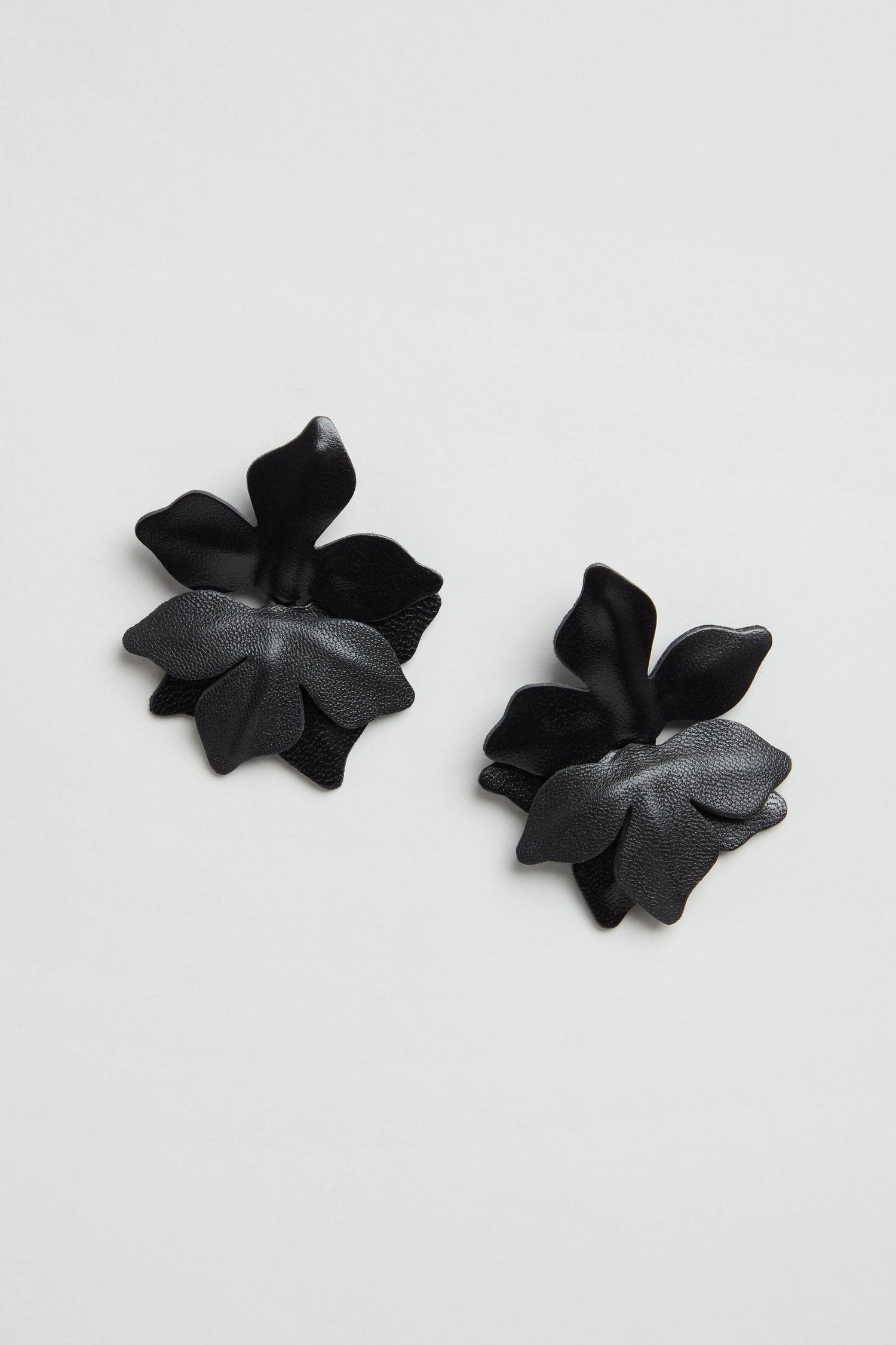 Metallic Leather Flower Earrings in black, featuring layered petal designs, are shown against a plain white background.