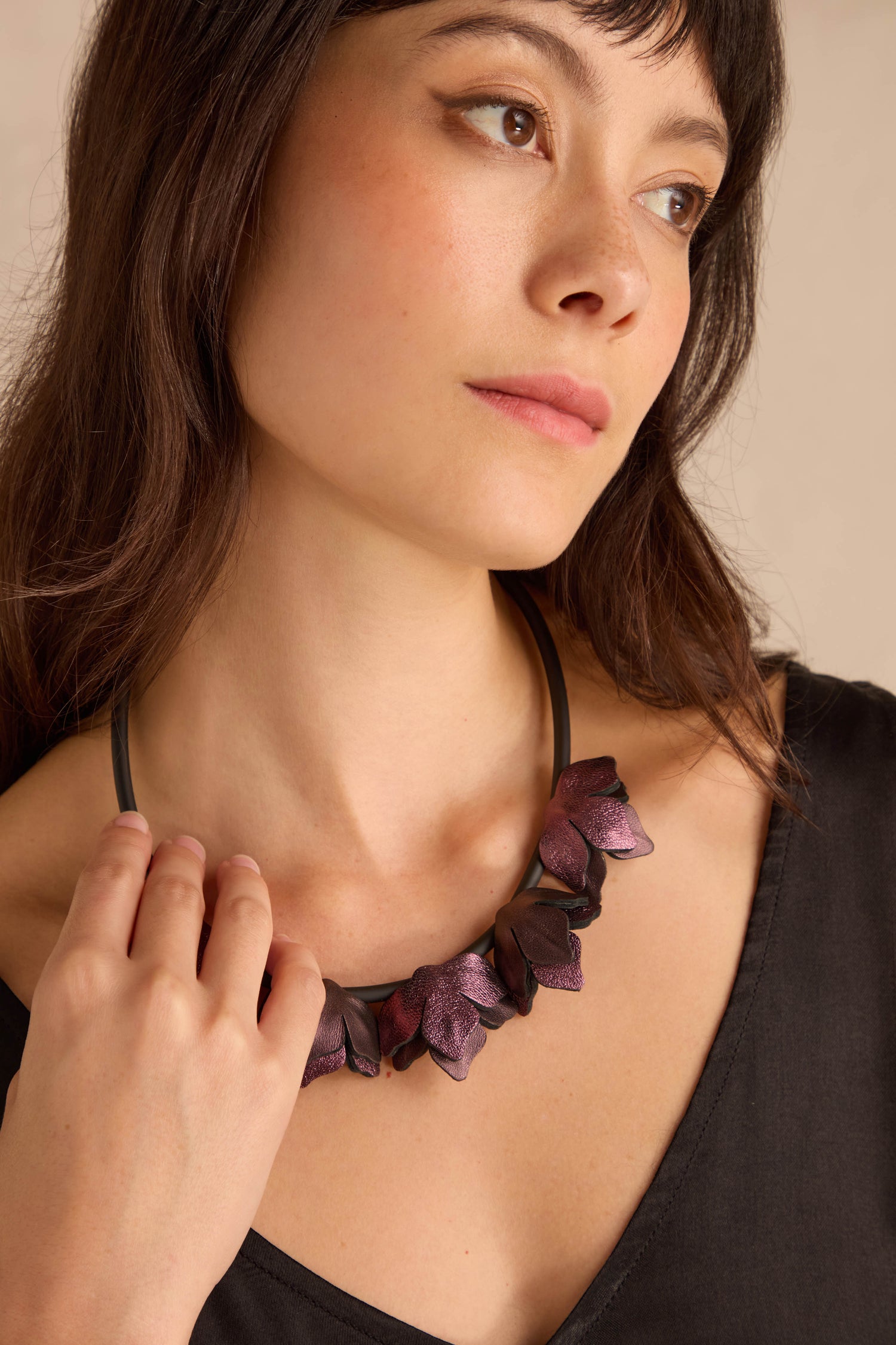 Woman wearing a Short Metallic Leather Petals Necklace and a black V-neck top, gazing off to the side.