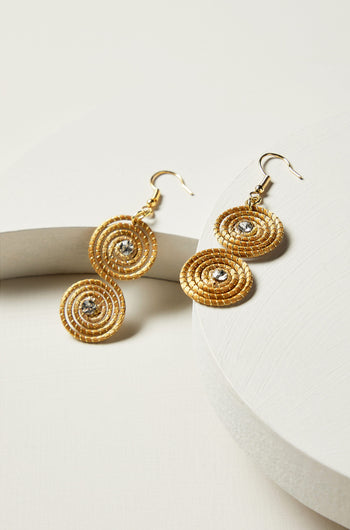 A pair of Golden Grass Spiral Rhinestone Earrings with silver accents resting on a white surface.