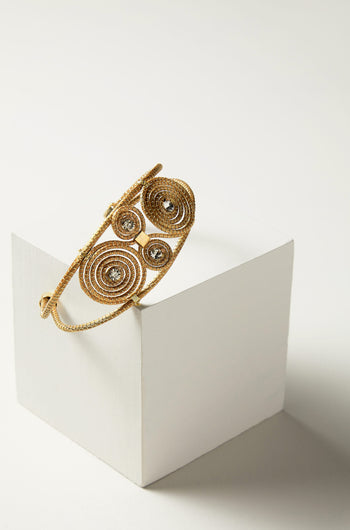 Golden Glass Spiral Rhinestone bracelet displayed on a white pedestal.