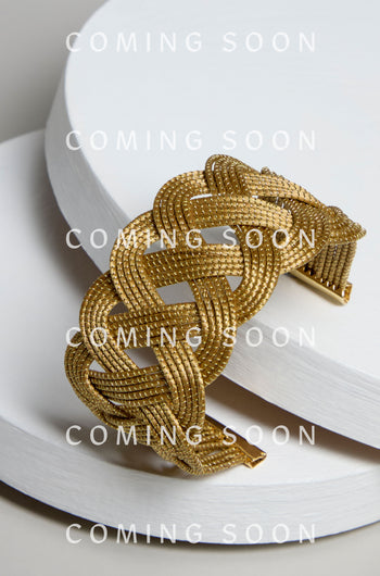 Golden Grass Woven Bracelet displayed on a minimal white backdrop with the text "COMING SOON" overlay. Discover the artisanal craftsmanship and sustainable elegance of this intricately braided golden piece.